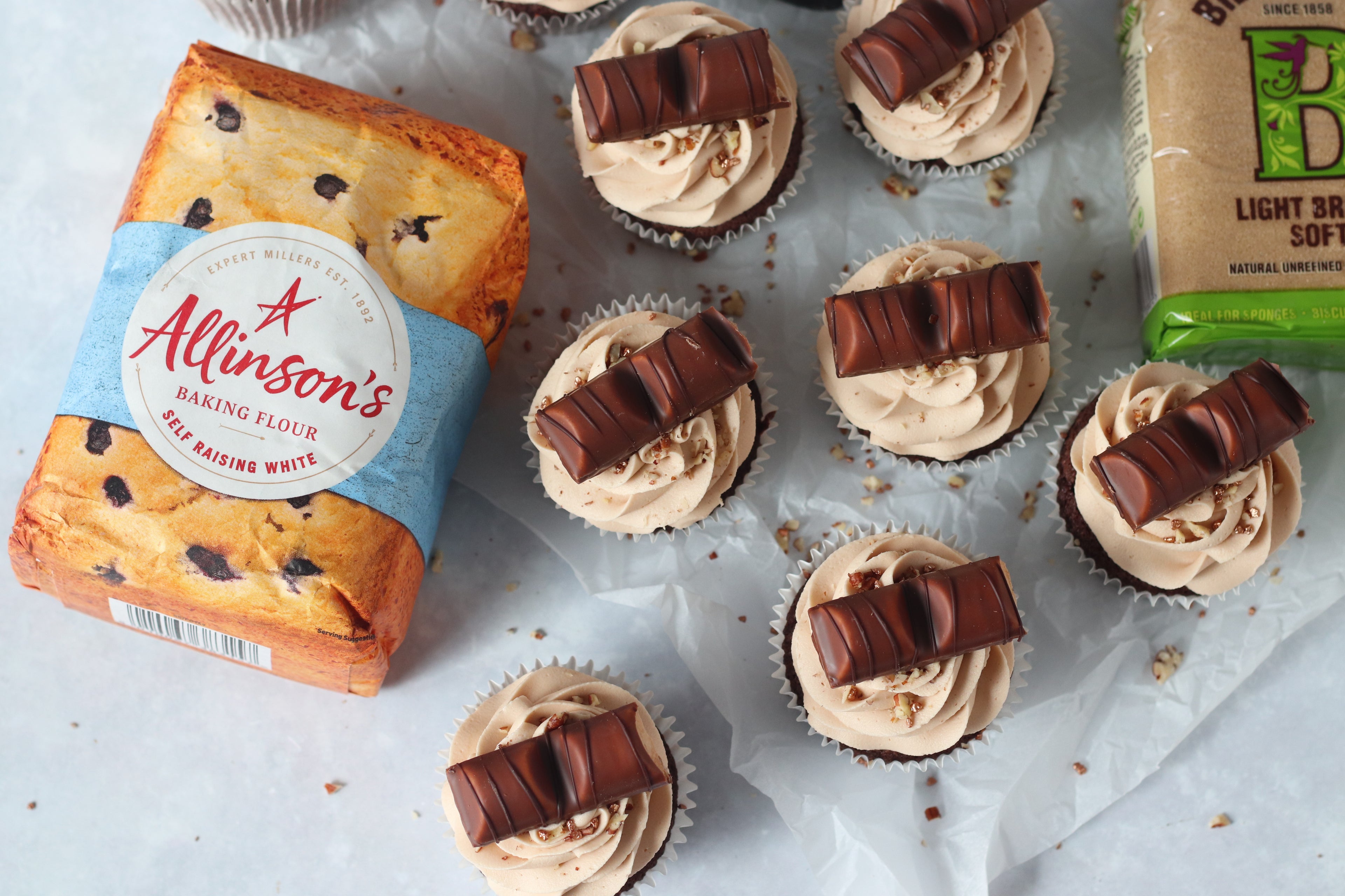 Overhead shot of 7 kinder bueno cupcakes with flour and sugar pack