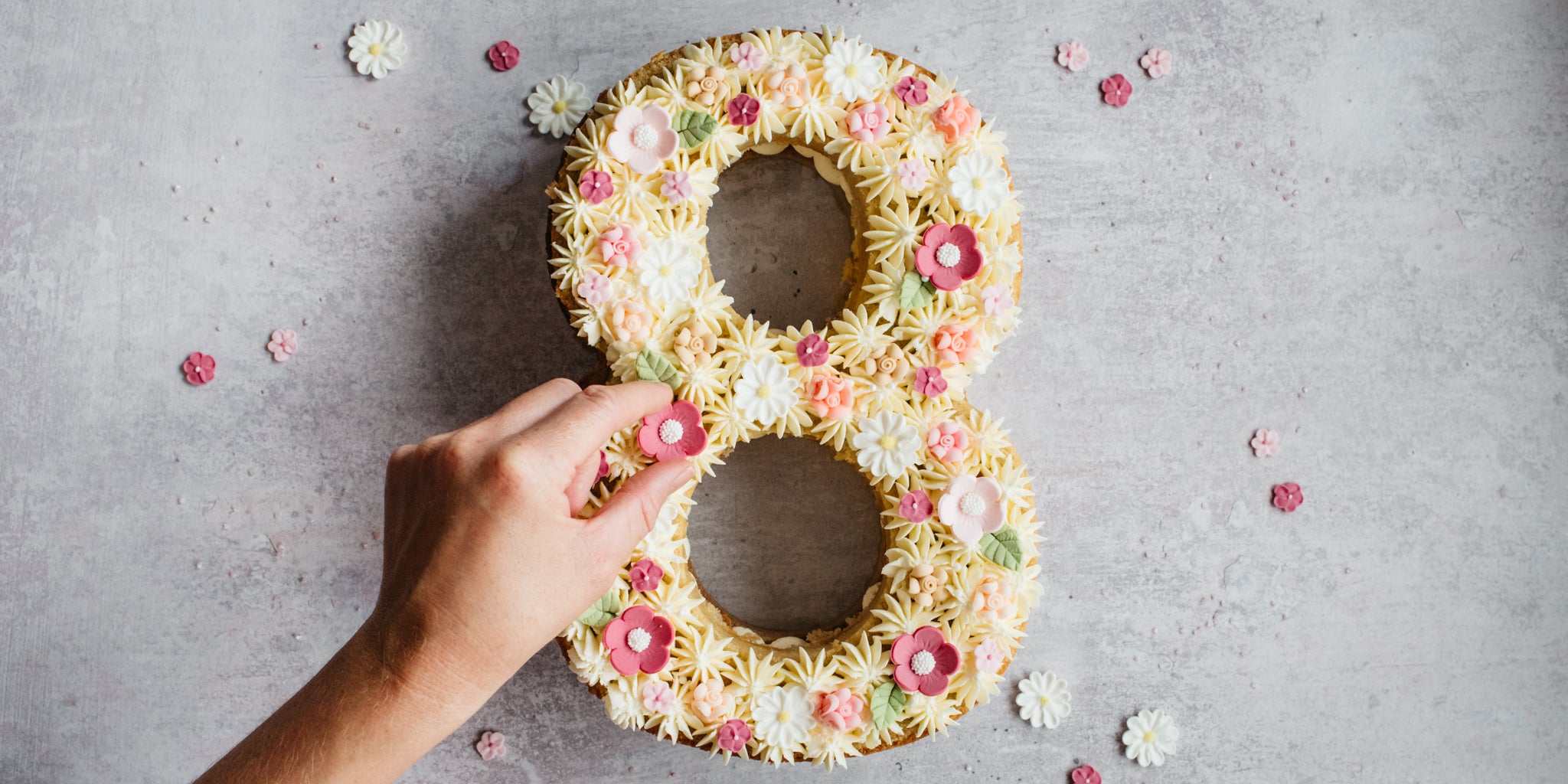 Top view of Number Cake being hand decorated with icing shapes, and piping patterns