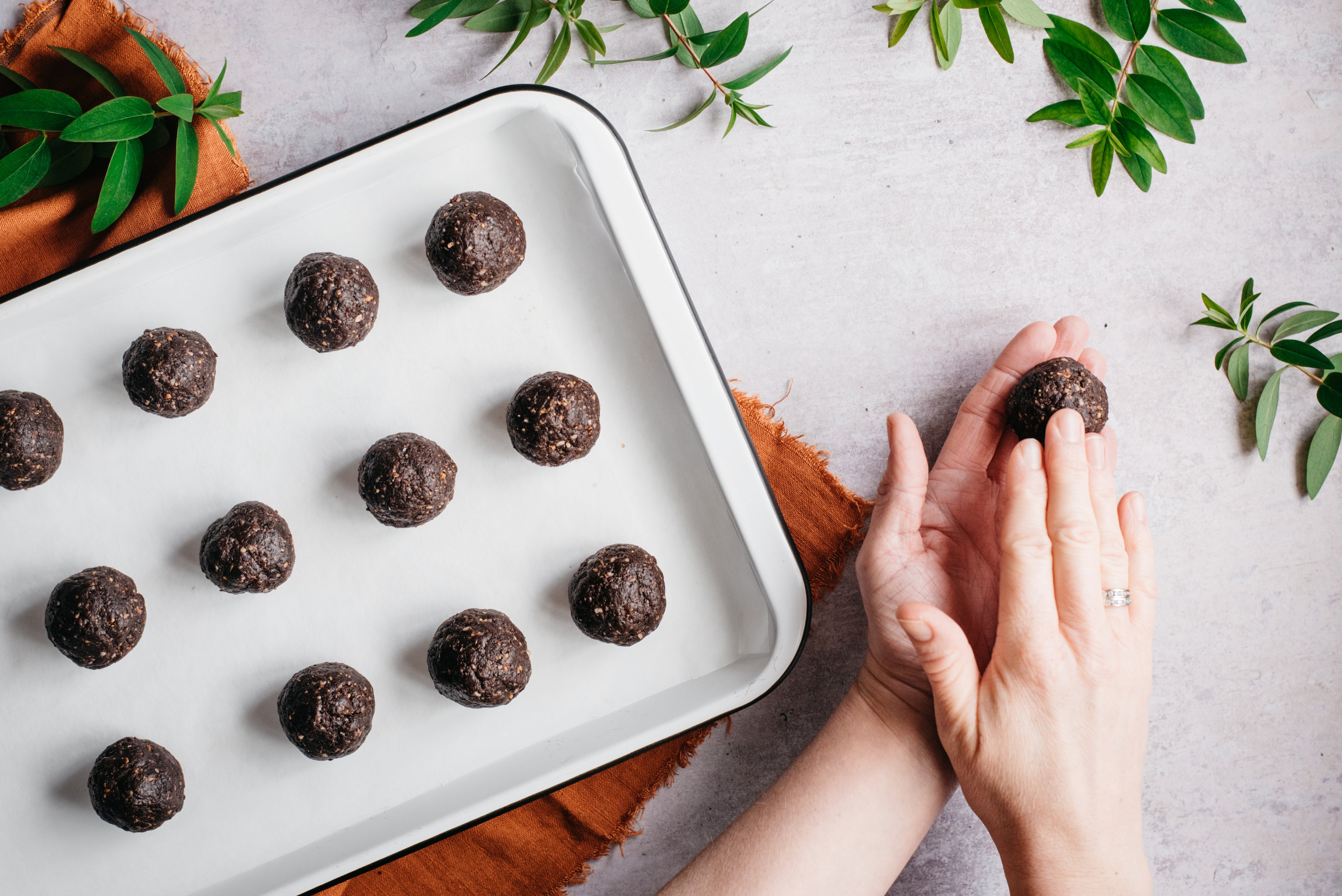 A hand rolling a raw vegan energy ball