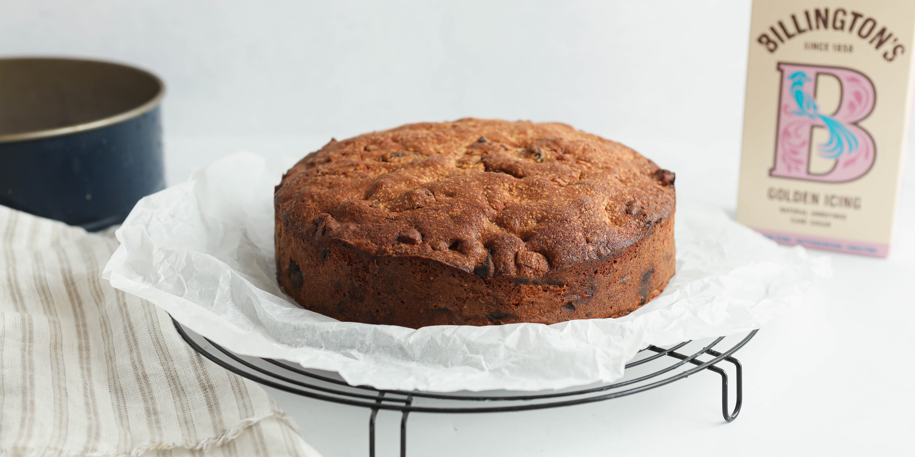 Fruit Cake cooling on a wire cooling rack, with a box of Billington's Golden Caster Icing sugar