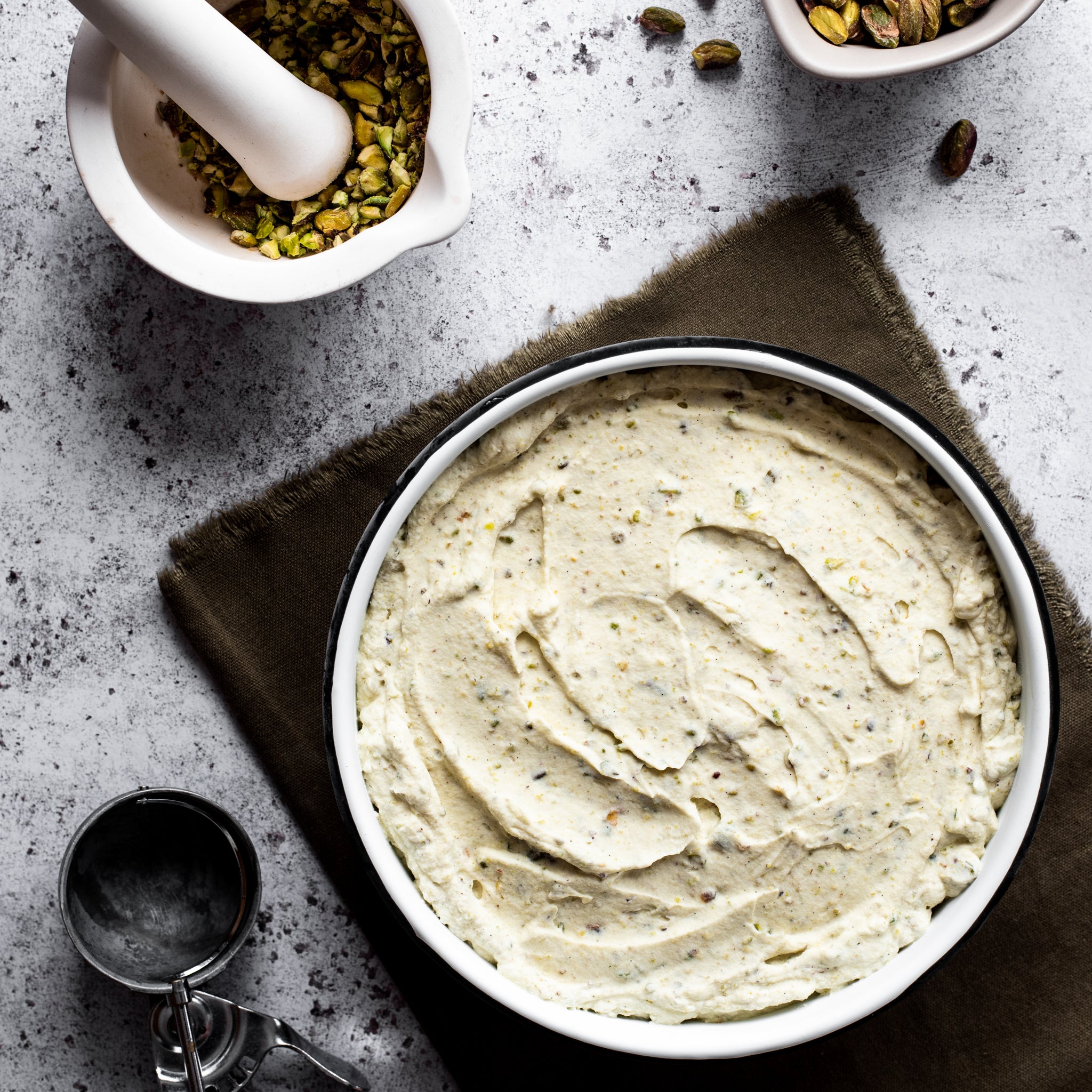 Pistachio ice cream mixture in a white bowl on a kitchen countertop