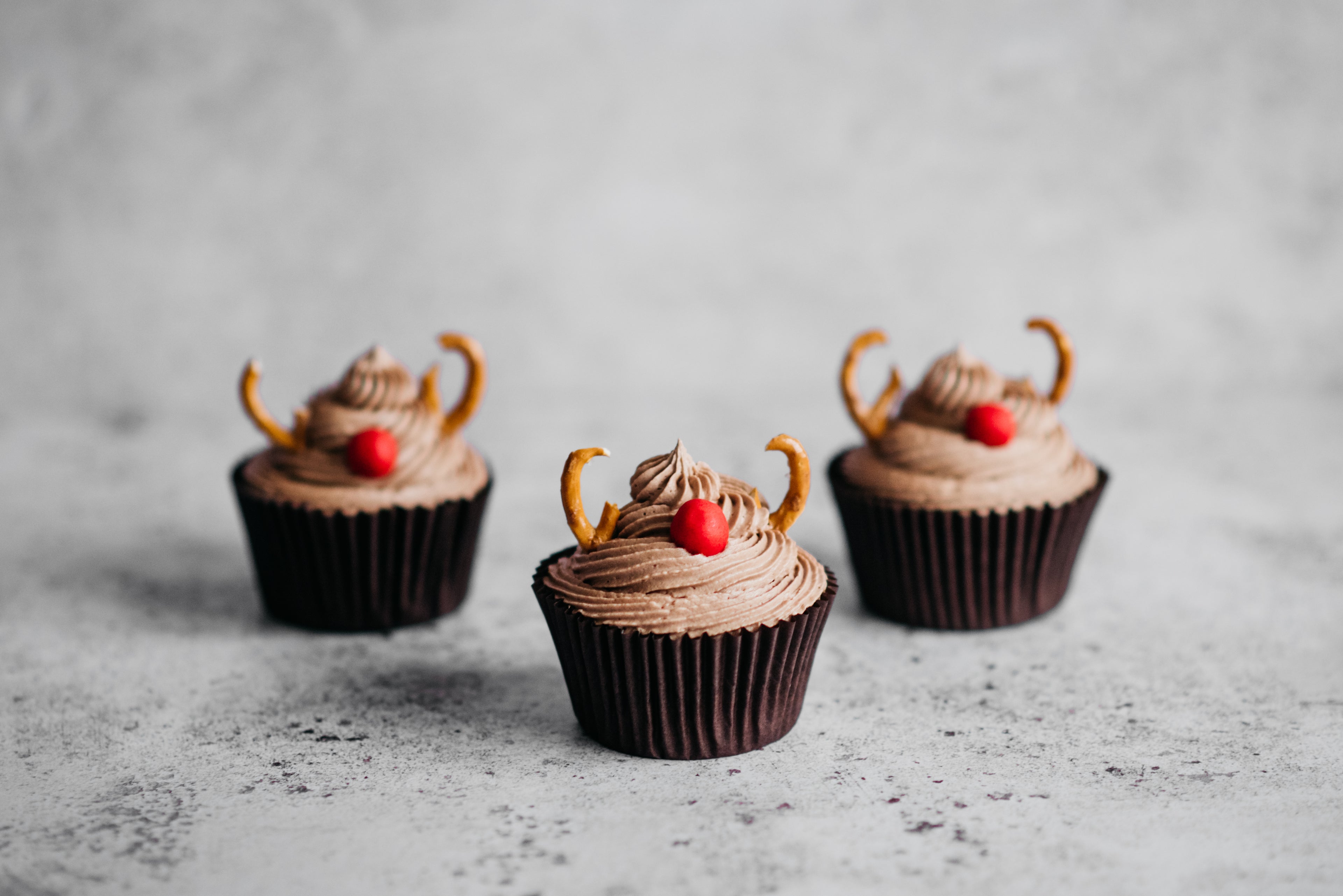 Close up of Reindeer Cupcakes decorated with pretzels and red sweets as a nose