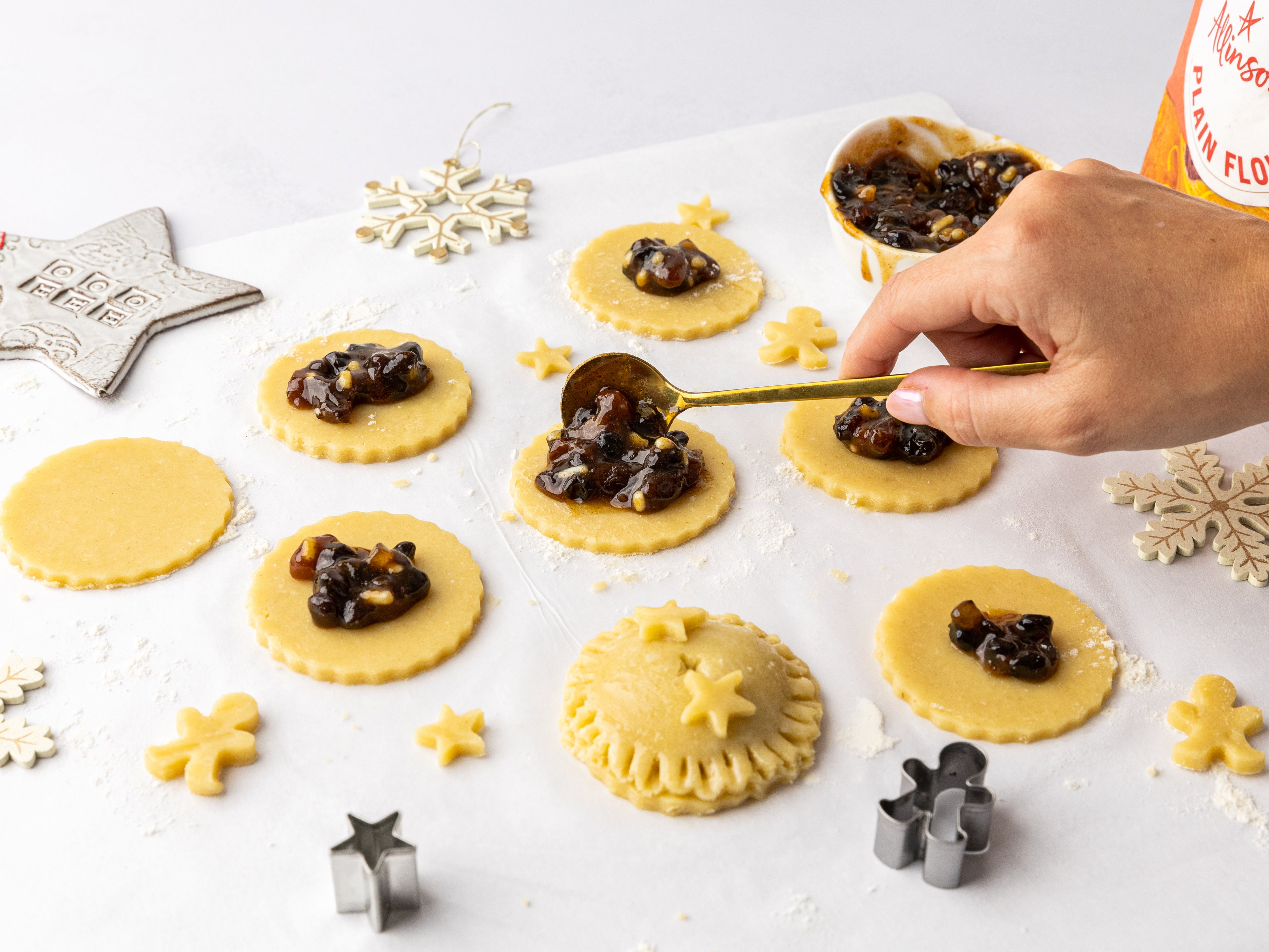 Hand spooning mincemeat into the centre of pastry rounds