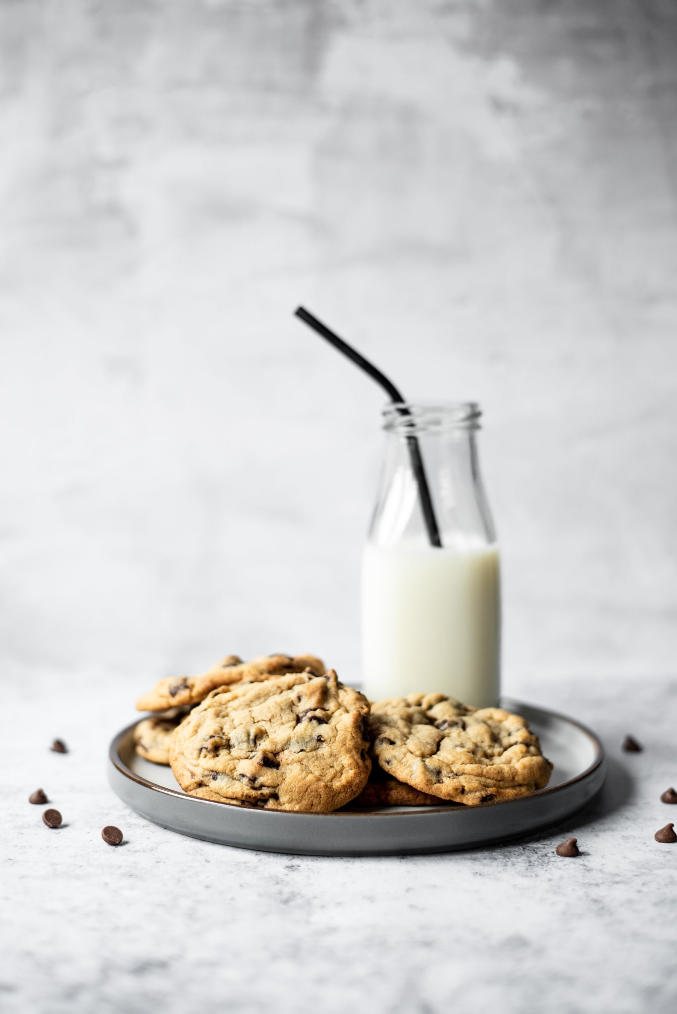 A plate of copycat millies cookies and a glass of milk in a bottle with a straw