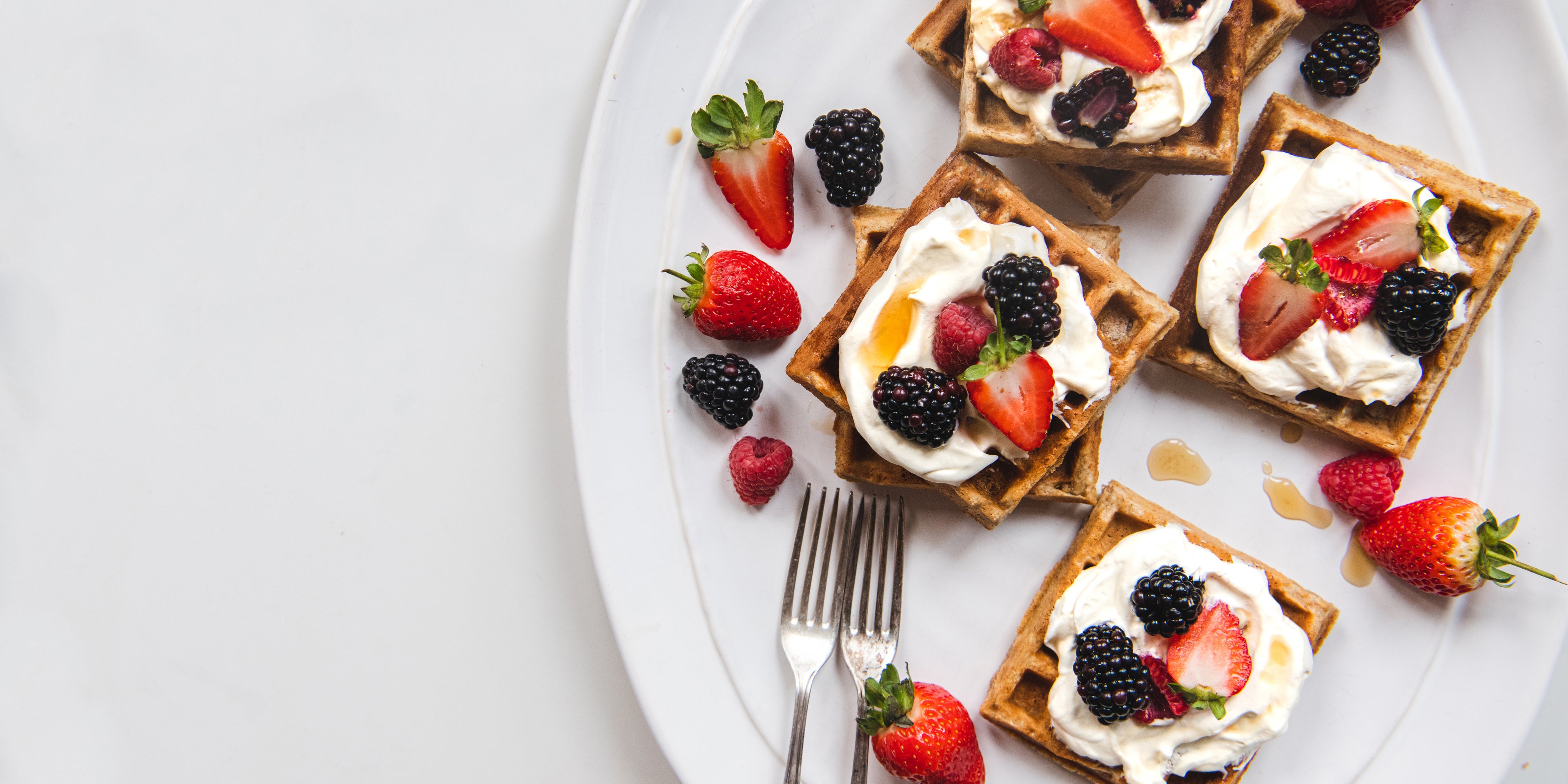 Top view of Wholemeal Banana Waffles topped with cream and fresh berries
