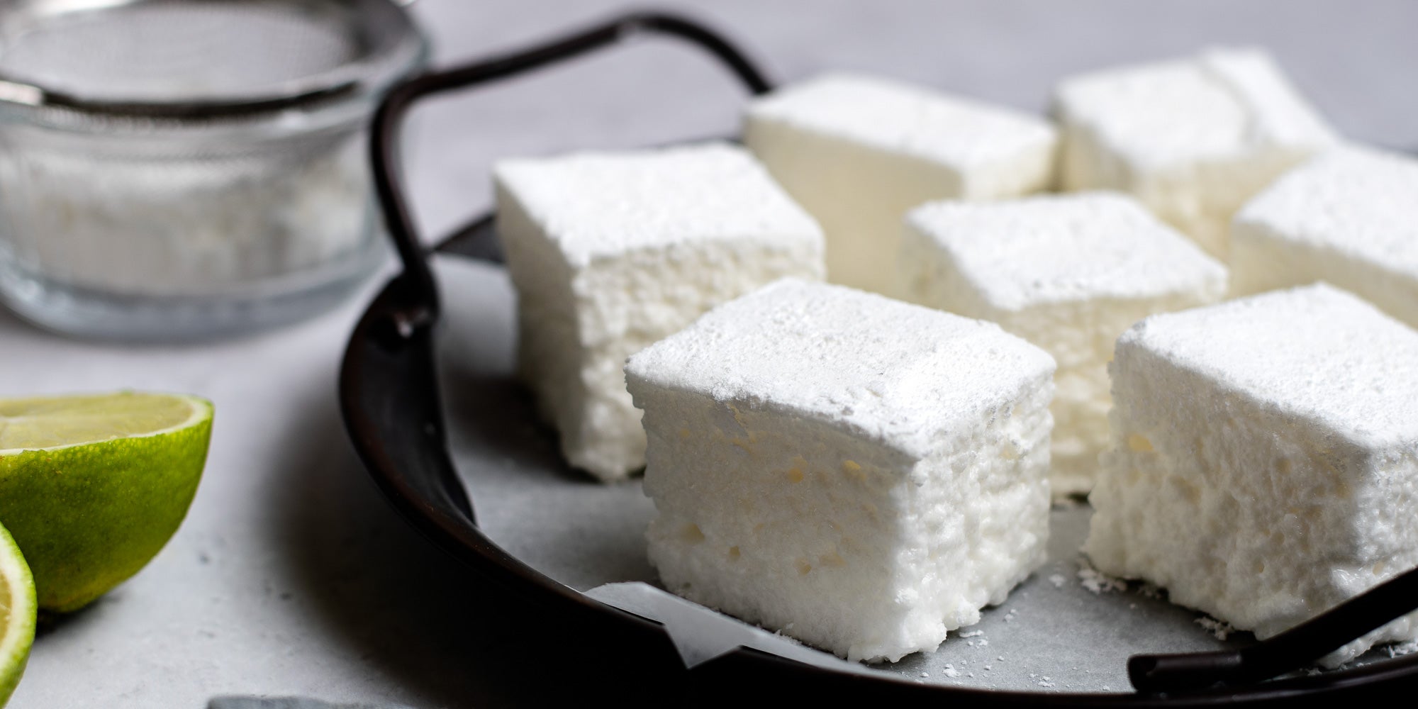 Gin & Tonic Marshmallows on baking paper on a tray with sliced limes