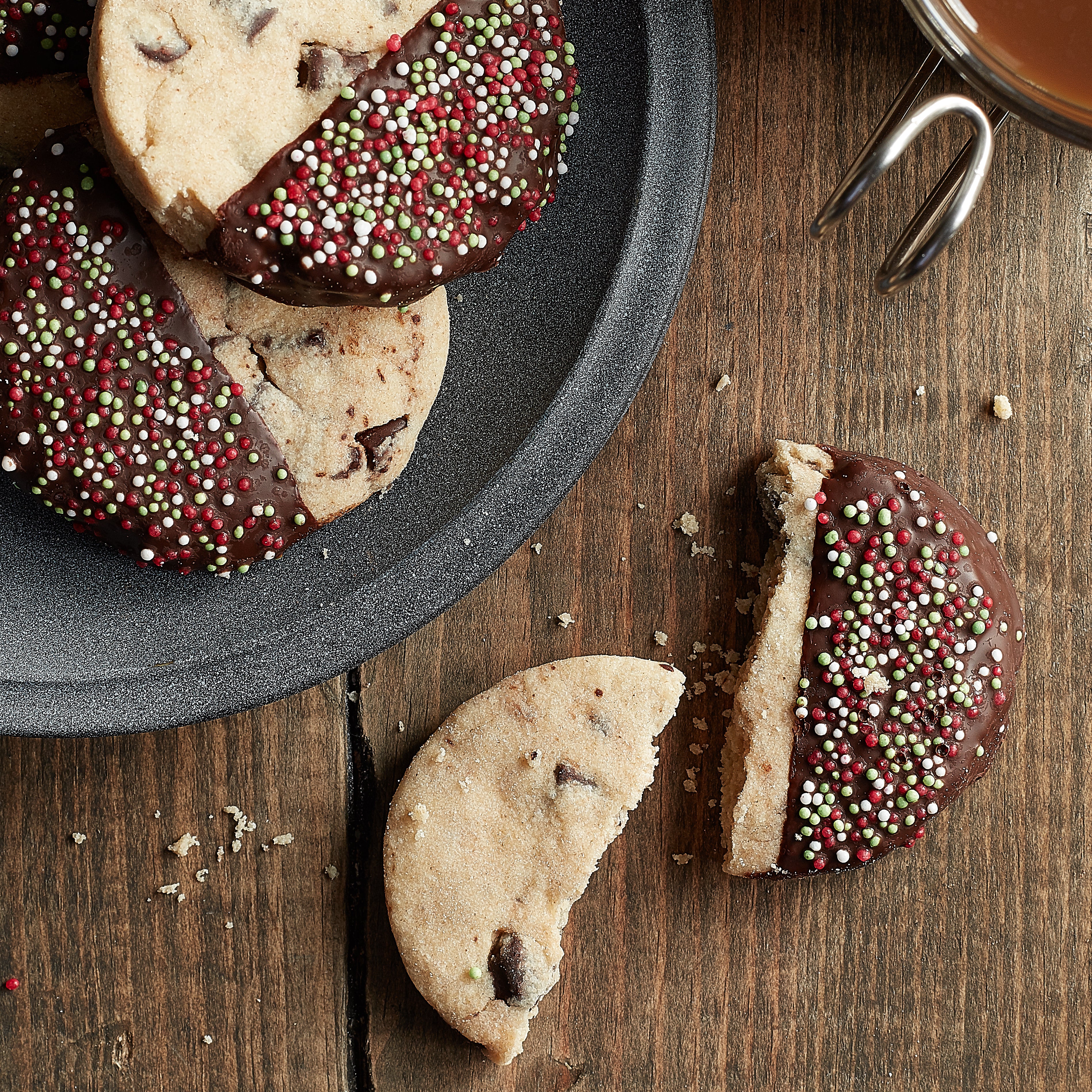 Two chocolate chunk shortbread dipped in chocolate and one broken in half