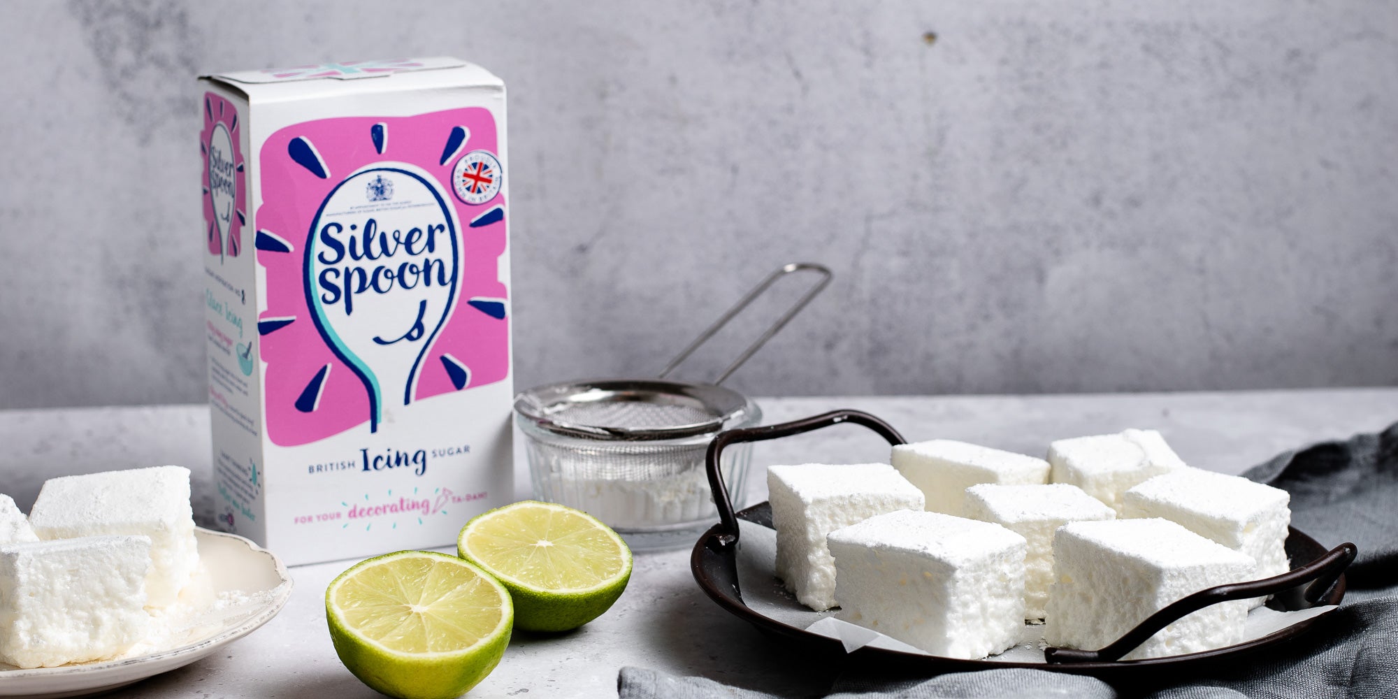 Gin & Tonic Marshmallows next to a box of Silver Spoon Icing Sugar with sliced lime
