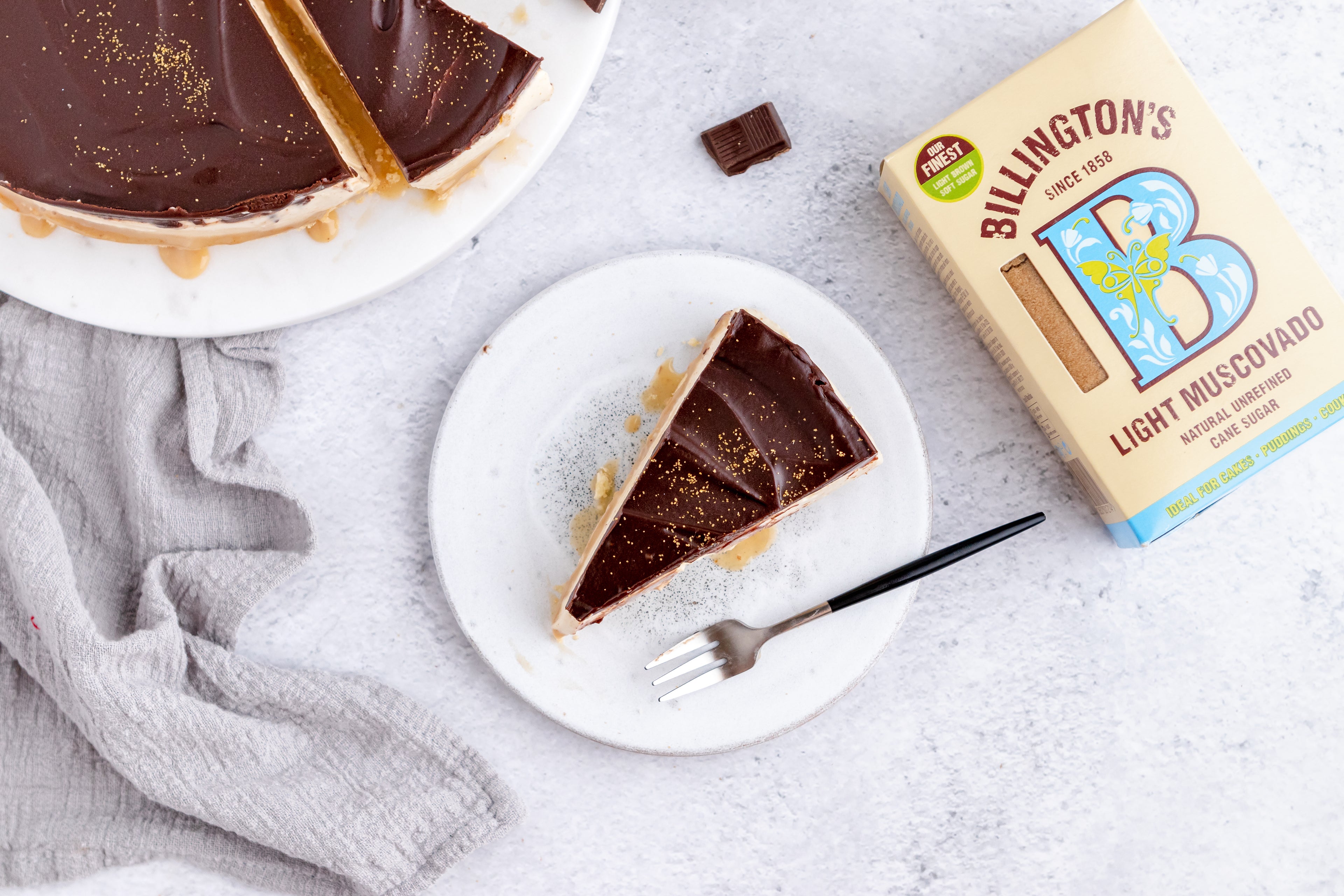 Millionaire's Cheesecake slice with a fork next to a box of Billington's Light Muscovado sugar