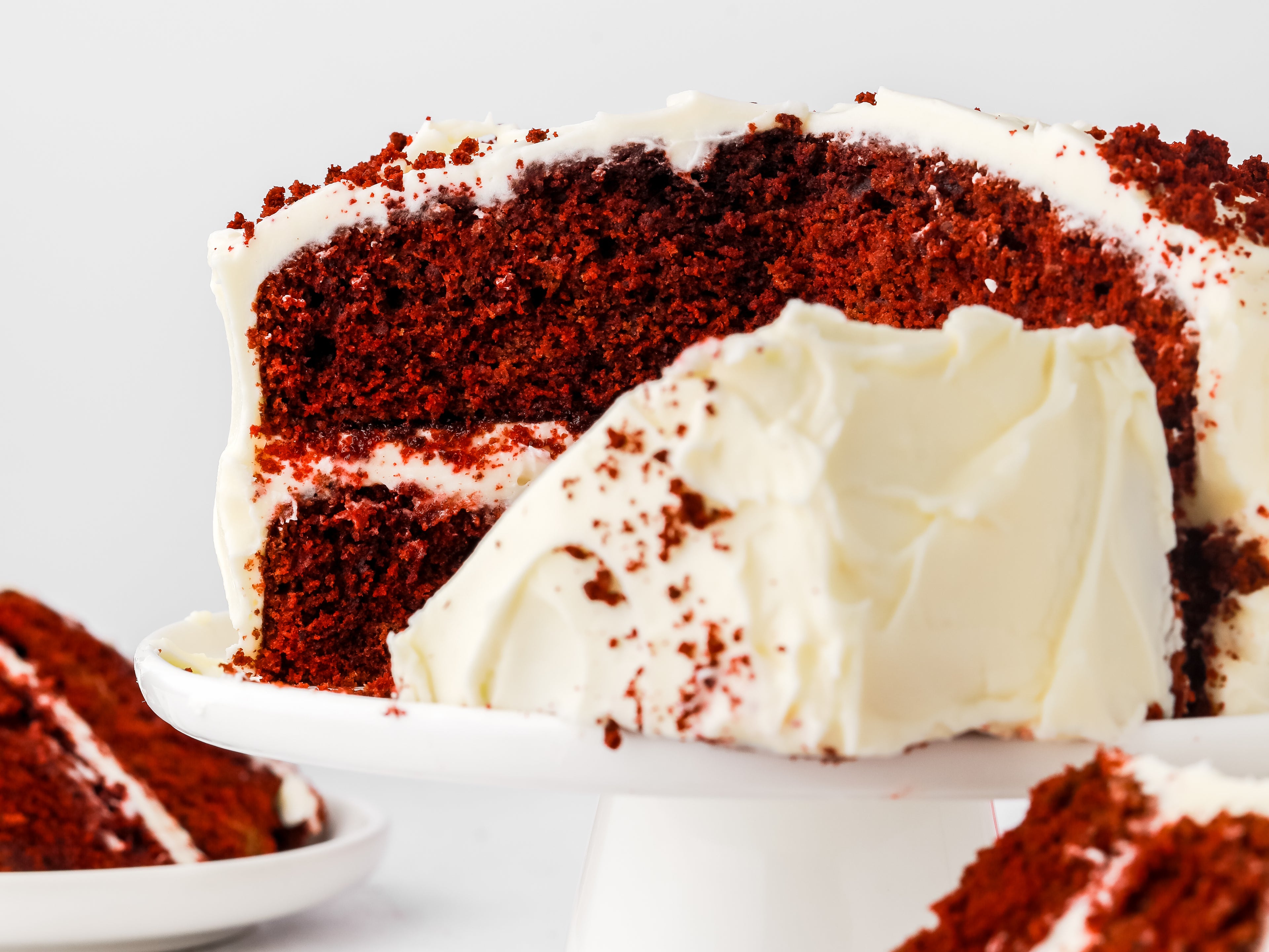 Cut red velvet cake with slice in front of it