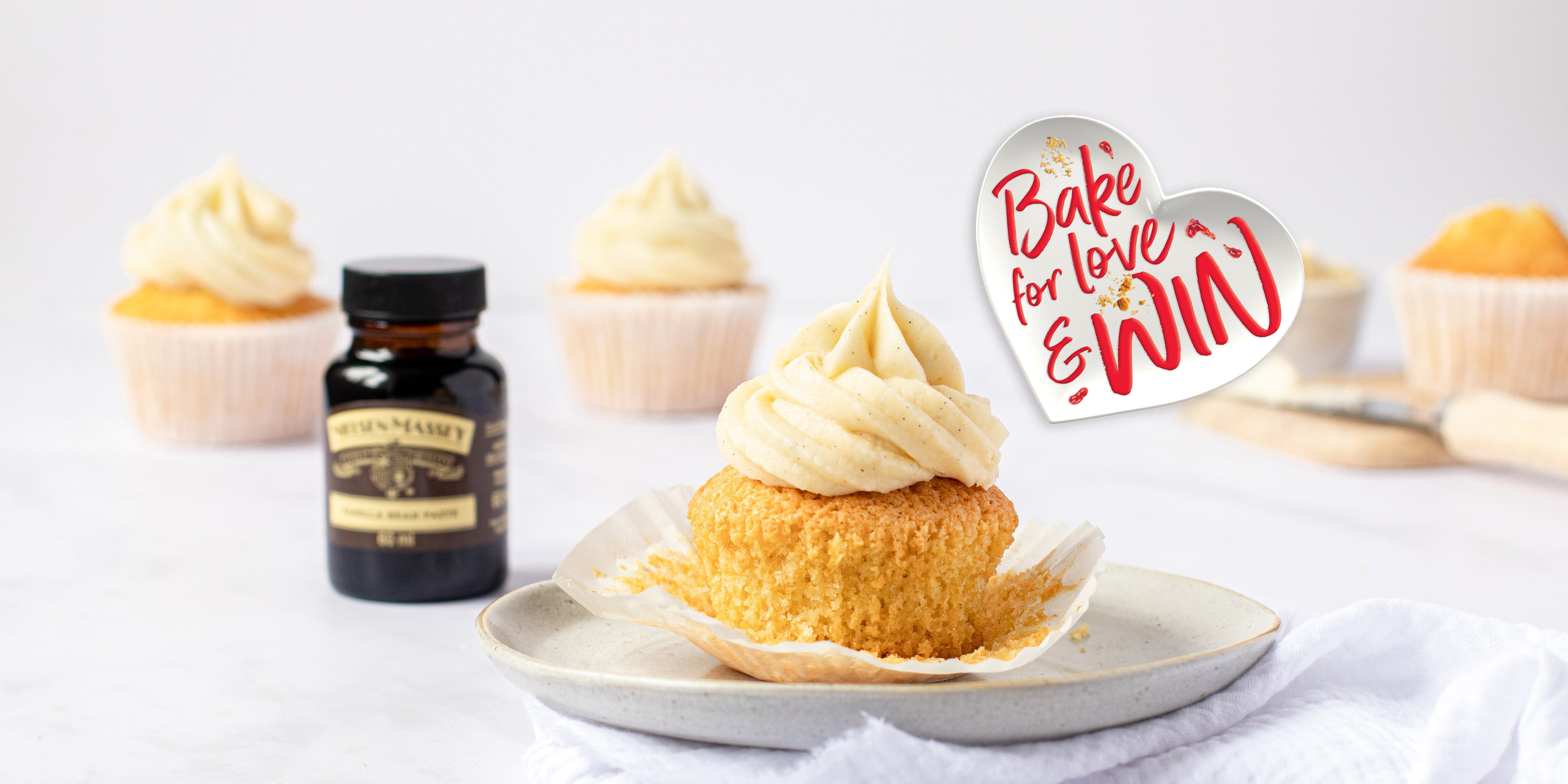 Close up shot of a vanilla cupcake next to a small jar of Neilsen Massey's vanilla extract