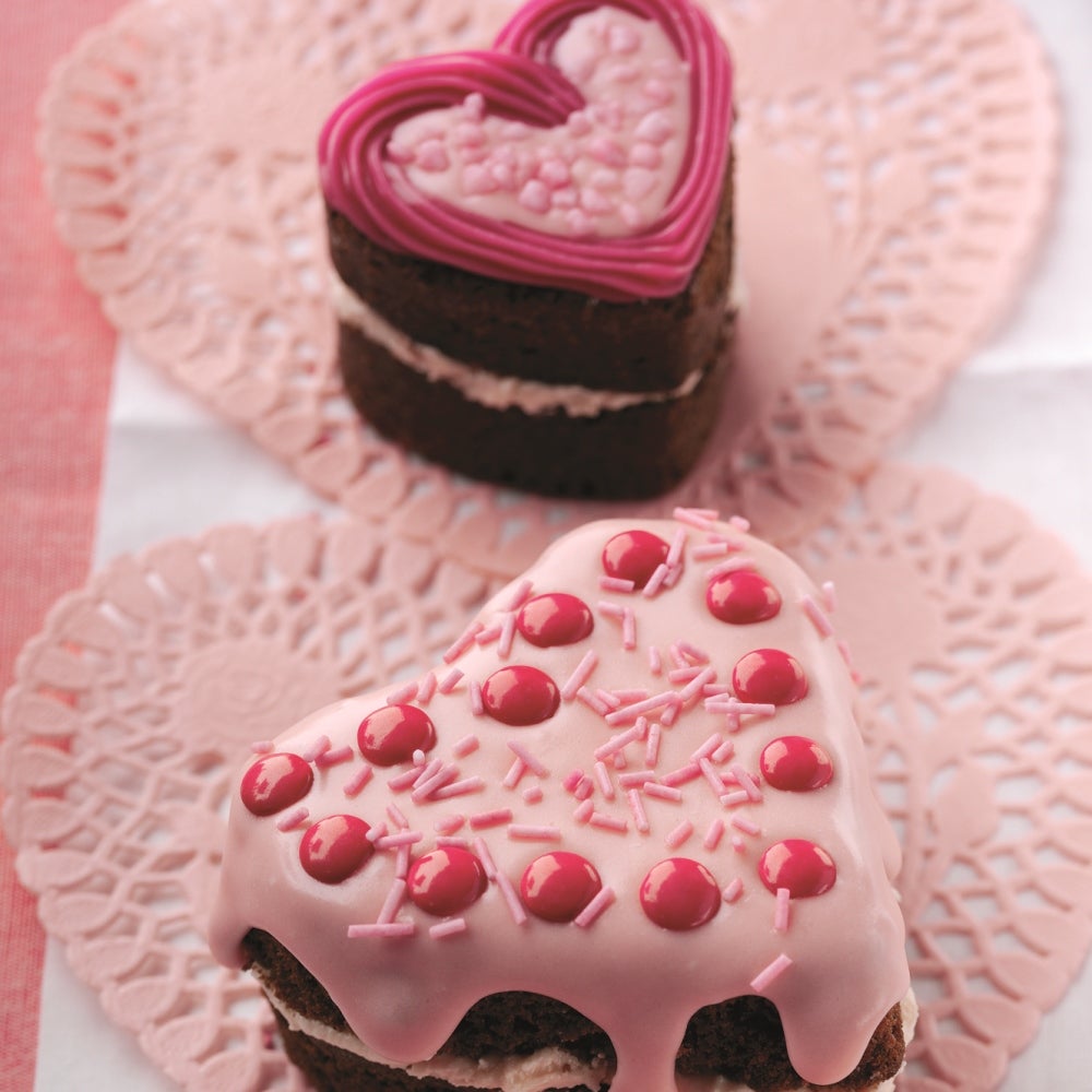 Heart-shaped cakes covered with pink icing and pink cake decorations 