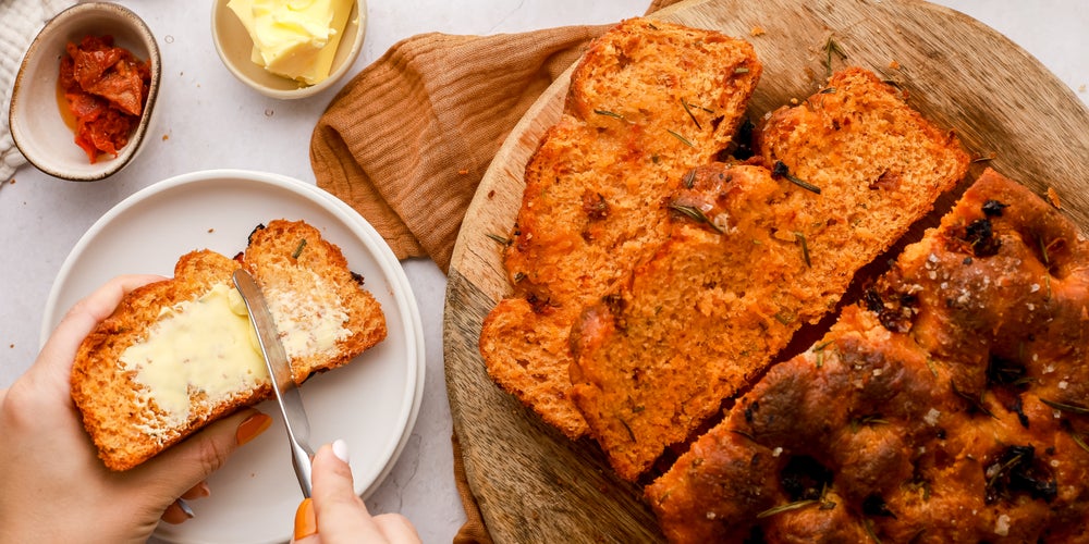 Buttering a slice of freshly-made sundried tomato bread