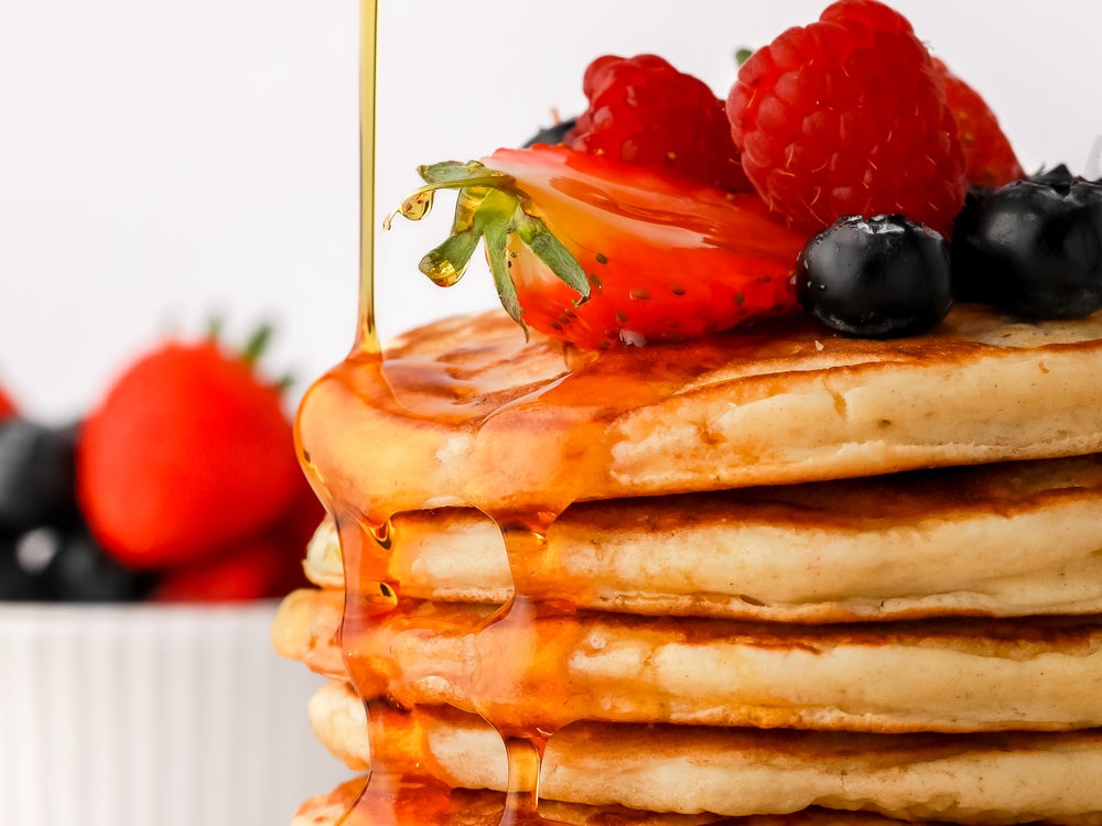 Super close up of syrup being poured on top of a pile of pancakes