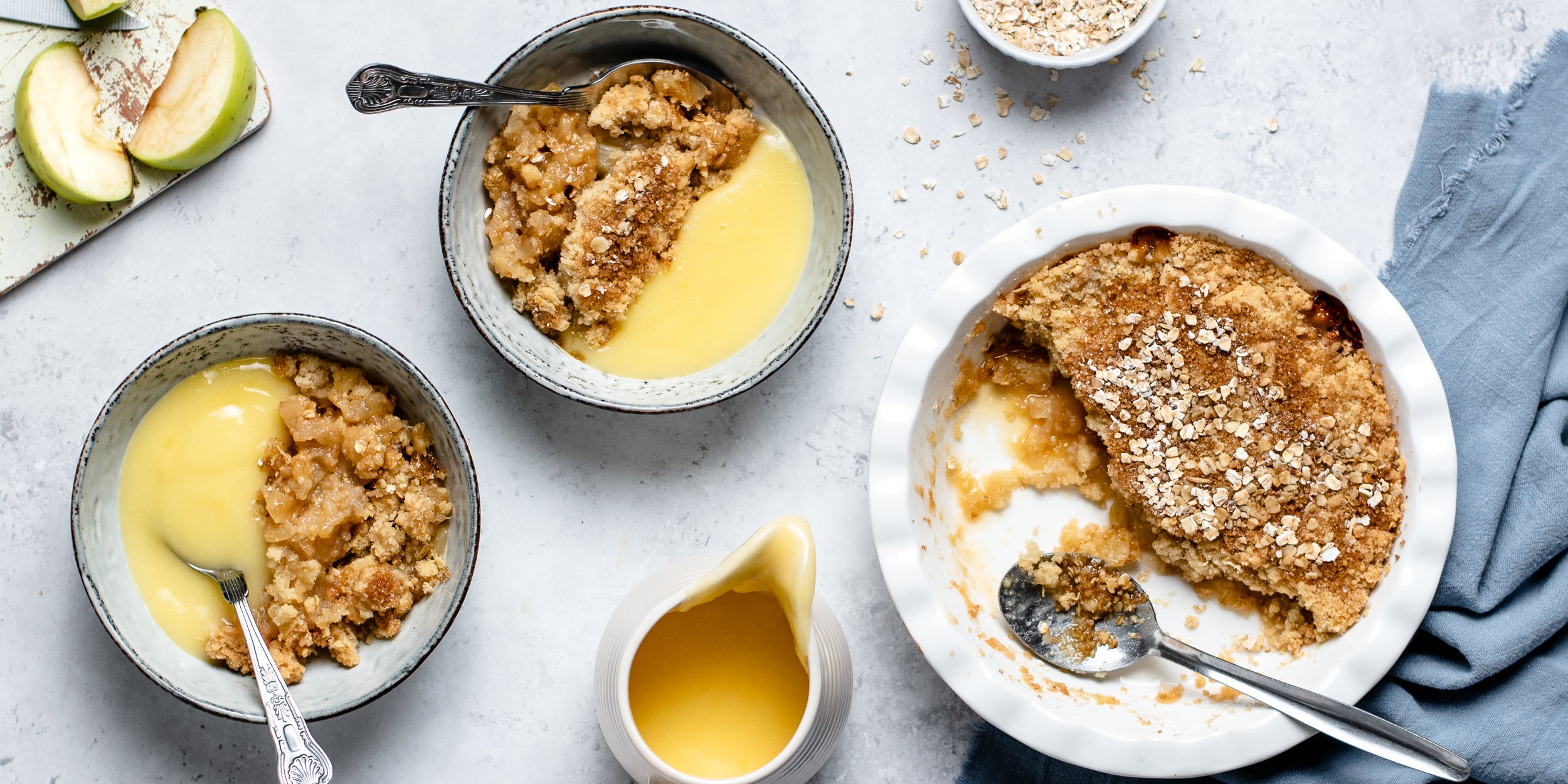Top view of Ultimate Apple Crumble served into bowls and drizzled with custard