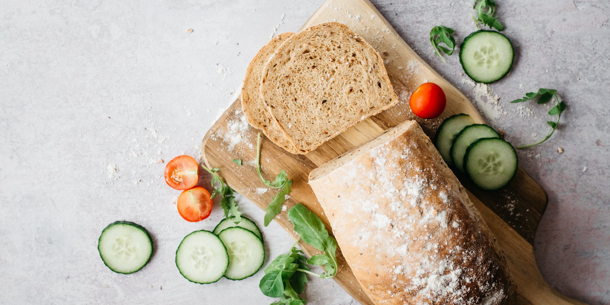 Top view of Farmhouse Country Grain Loaf with two slices cut. Garnished with cucumber, tomatoes and lettuce