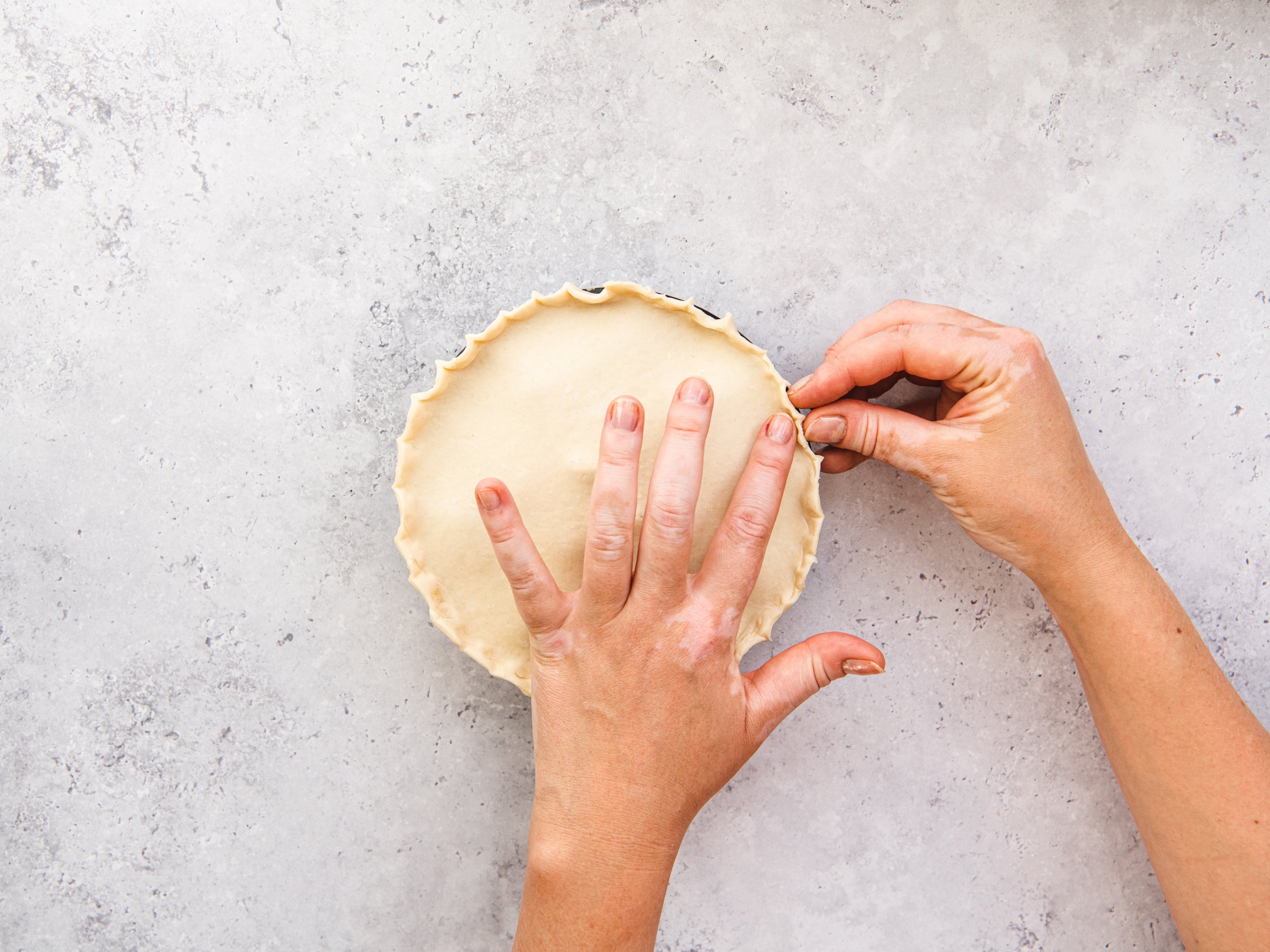 Folding the pastry base for a steak pie around a medium-sized pie dish