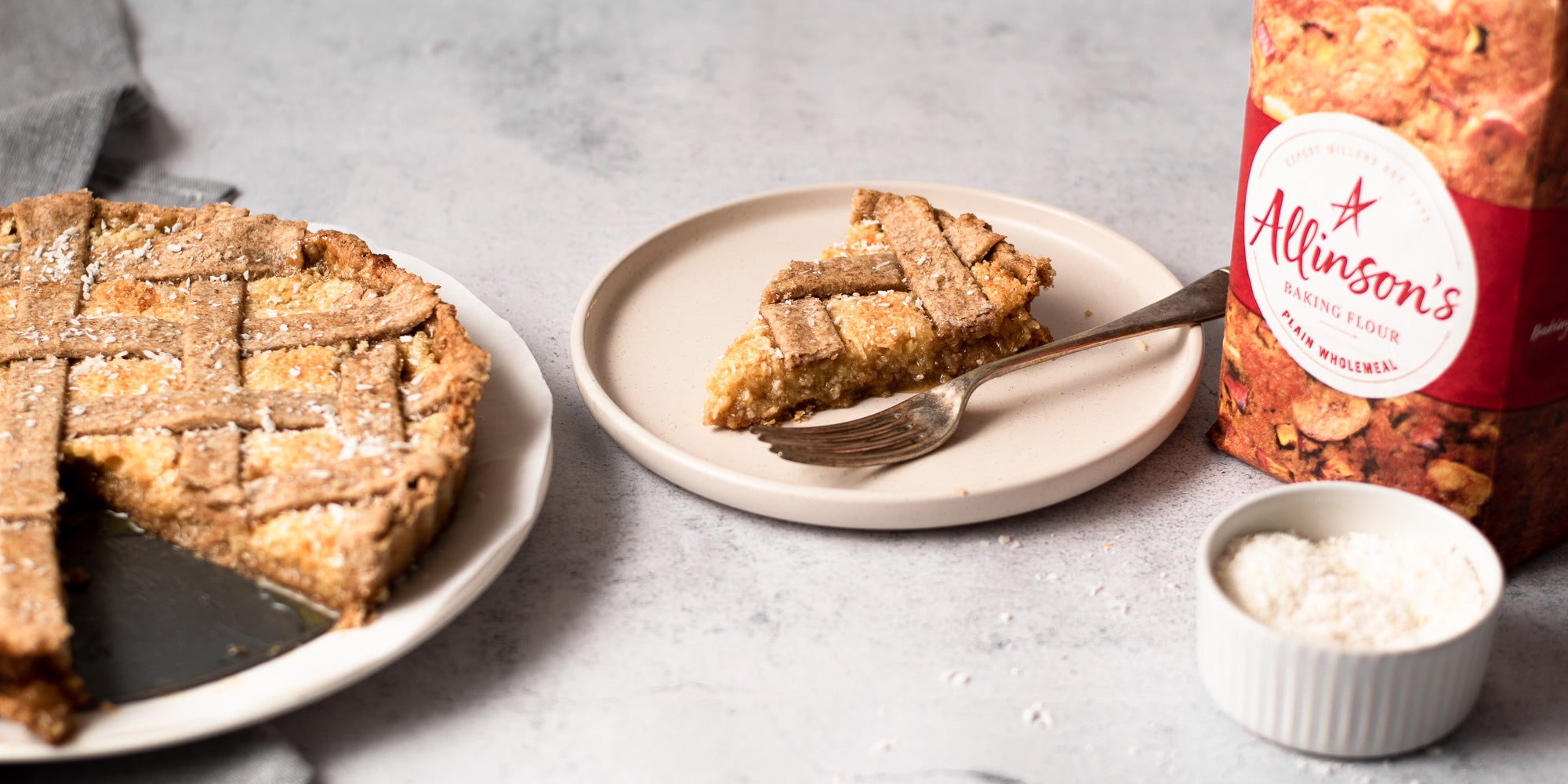 slice of coconut tart on a plate next to a bag of flour