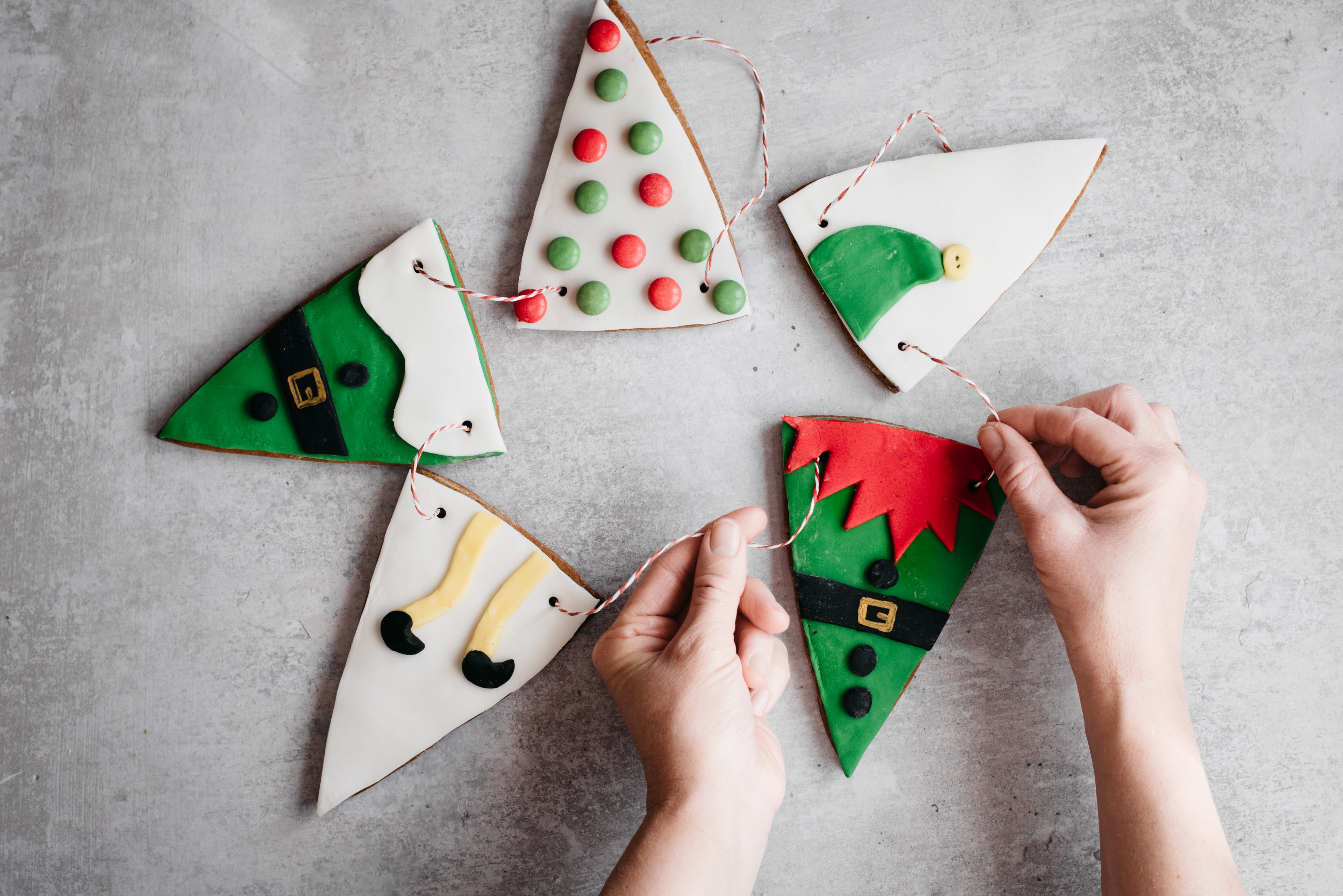 HoHoHo Elf Bunting close up, decorated with elf designs and hands threading the bunting with twine