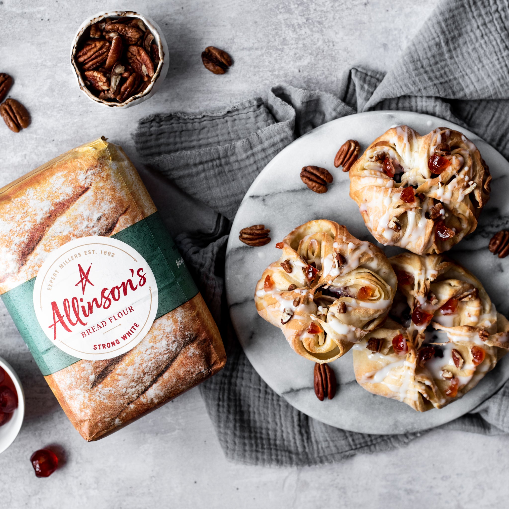 Overhead shot of 3 danish pastries on a plate with pecan nuts and flour pack