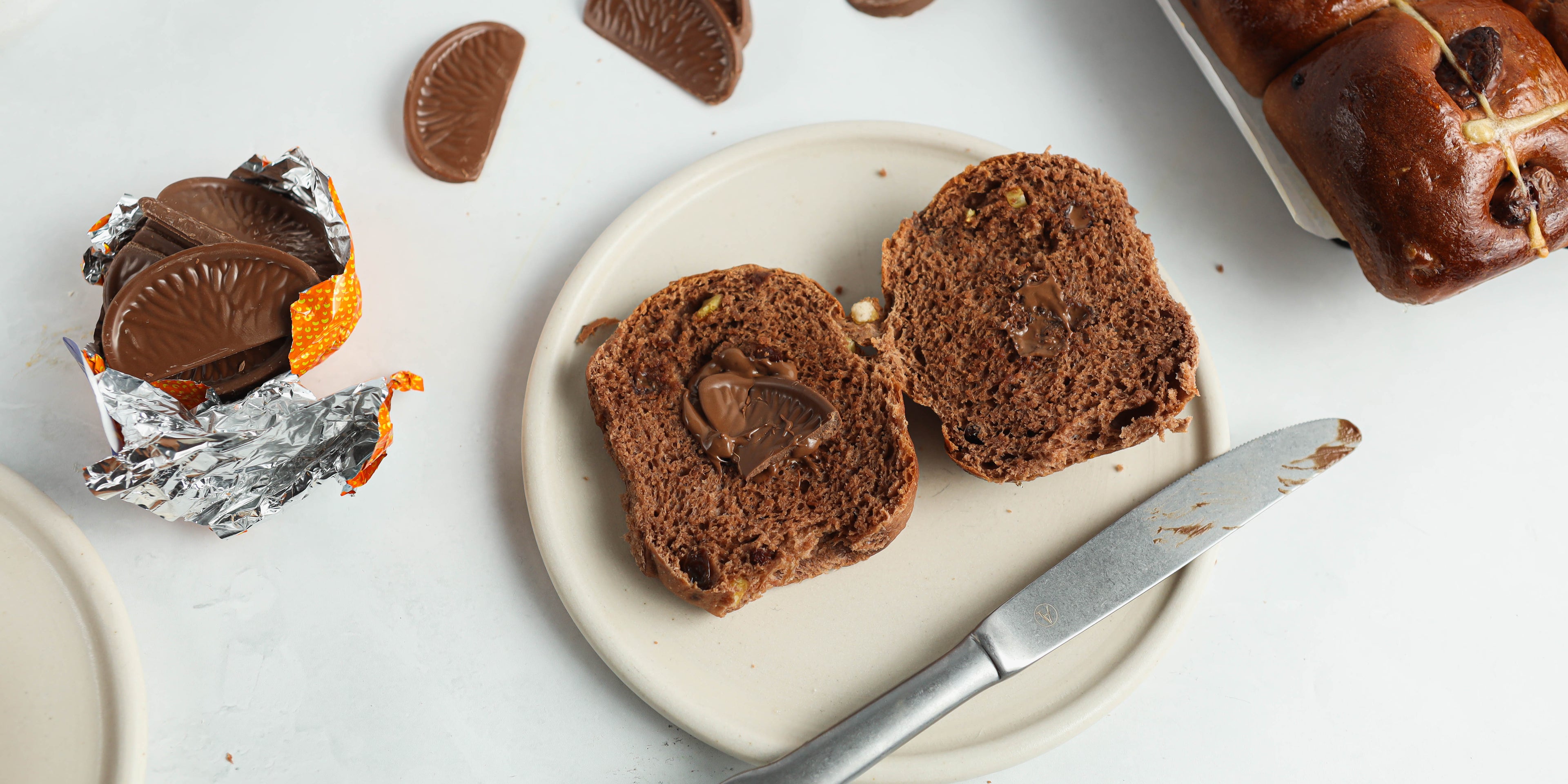 Close up of a chocolate hot cross bun sliced in half next to a Terry's Chocolate Orange