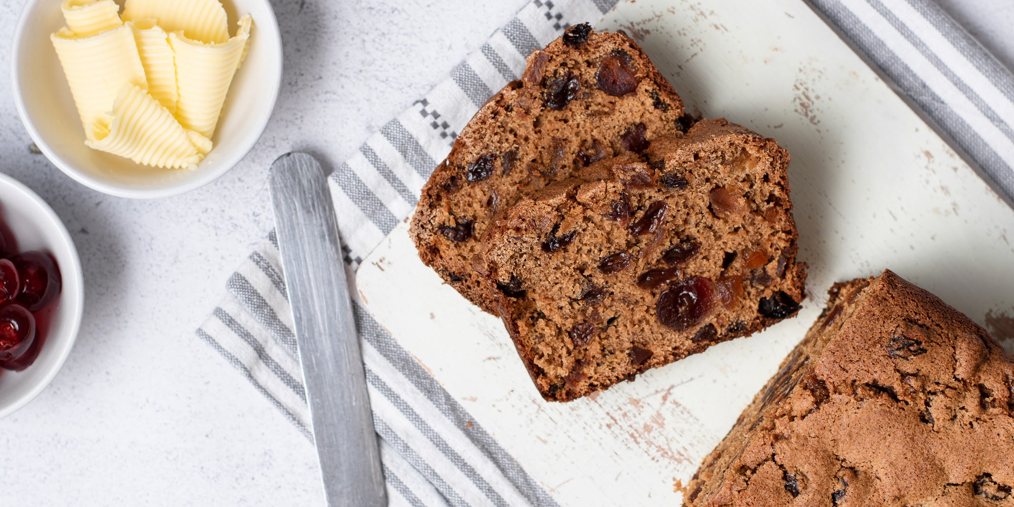 Sliced Irish Tea Brack on a striped cloth, with a knife and butter