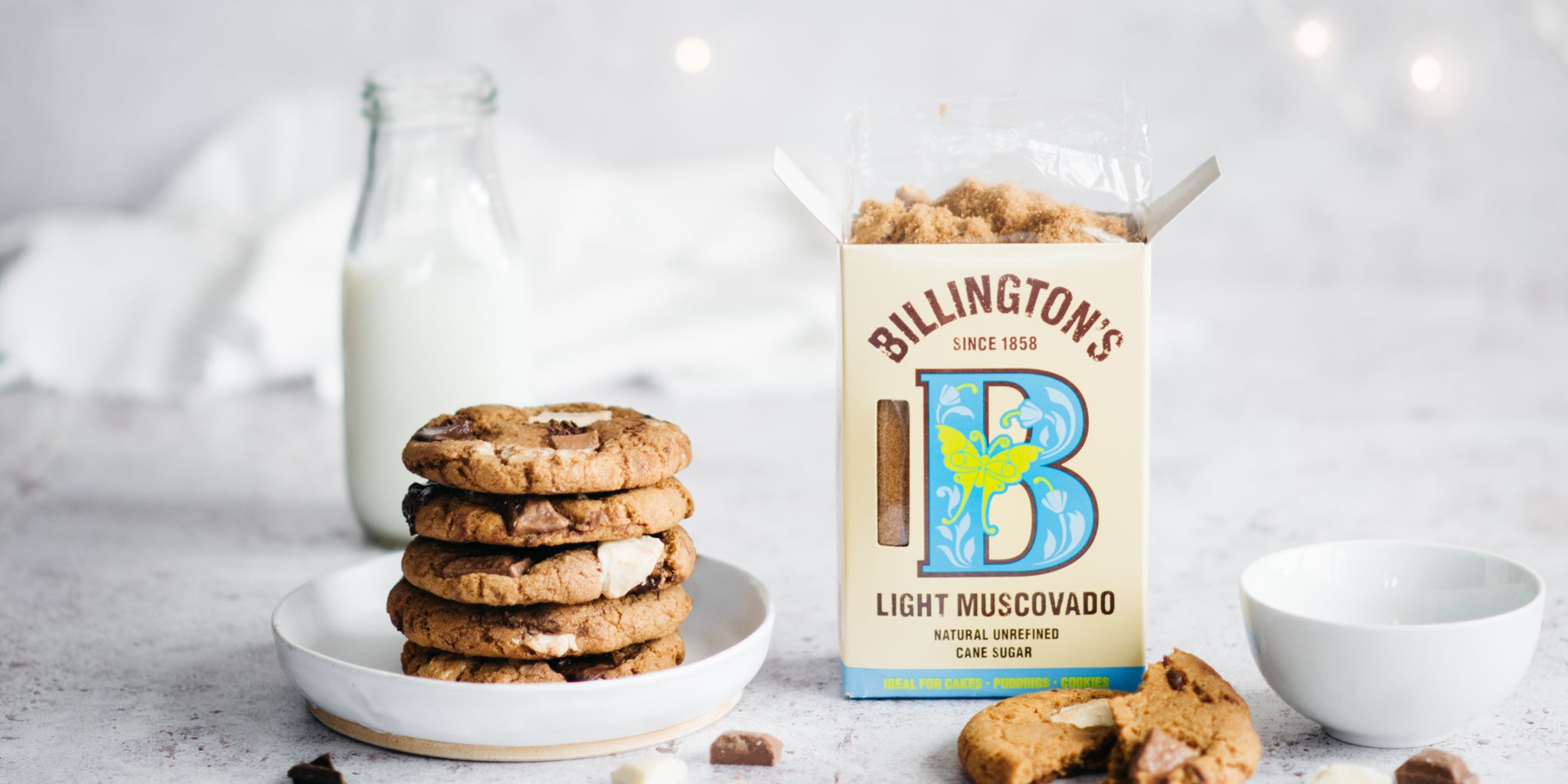 Stack of cookies on a white plate with a box of sugar open next to it