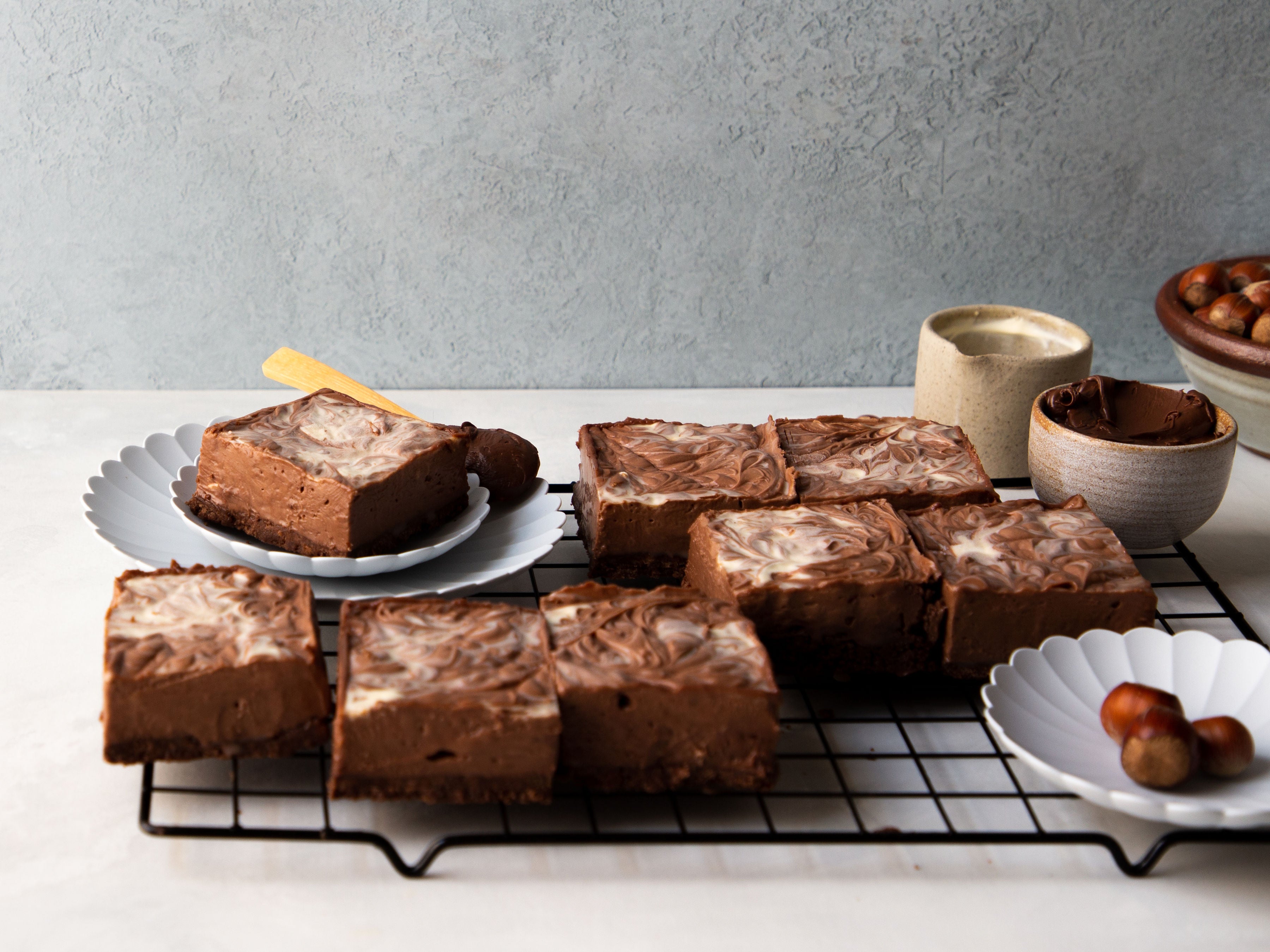 Nutella Cheesecake Bars on a wire rack, being served on plates.