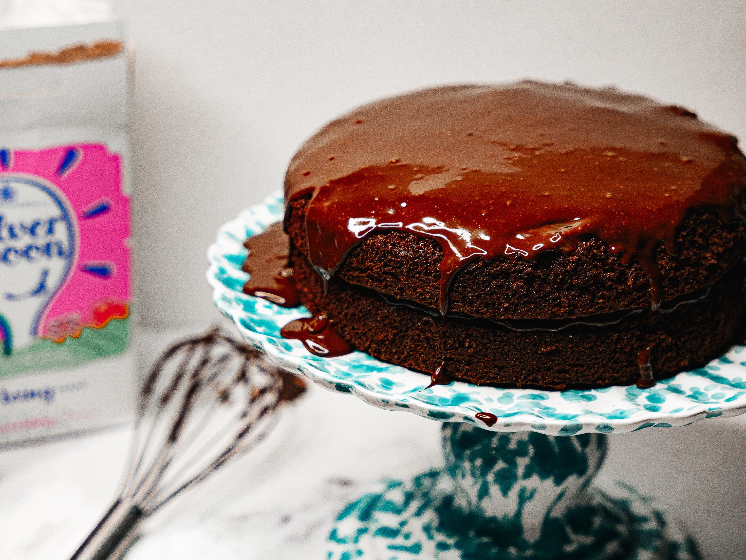 Mary Berry chocolate cake covered with thick chocolate icing on a multicoloured cake stand