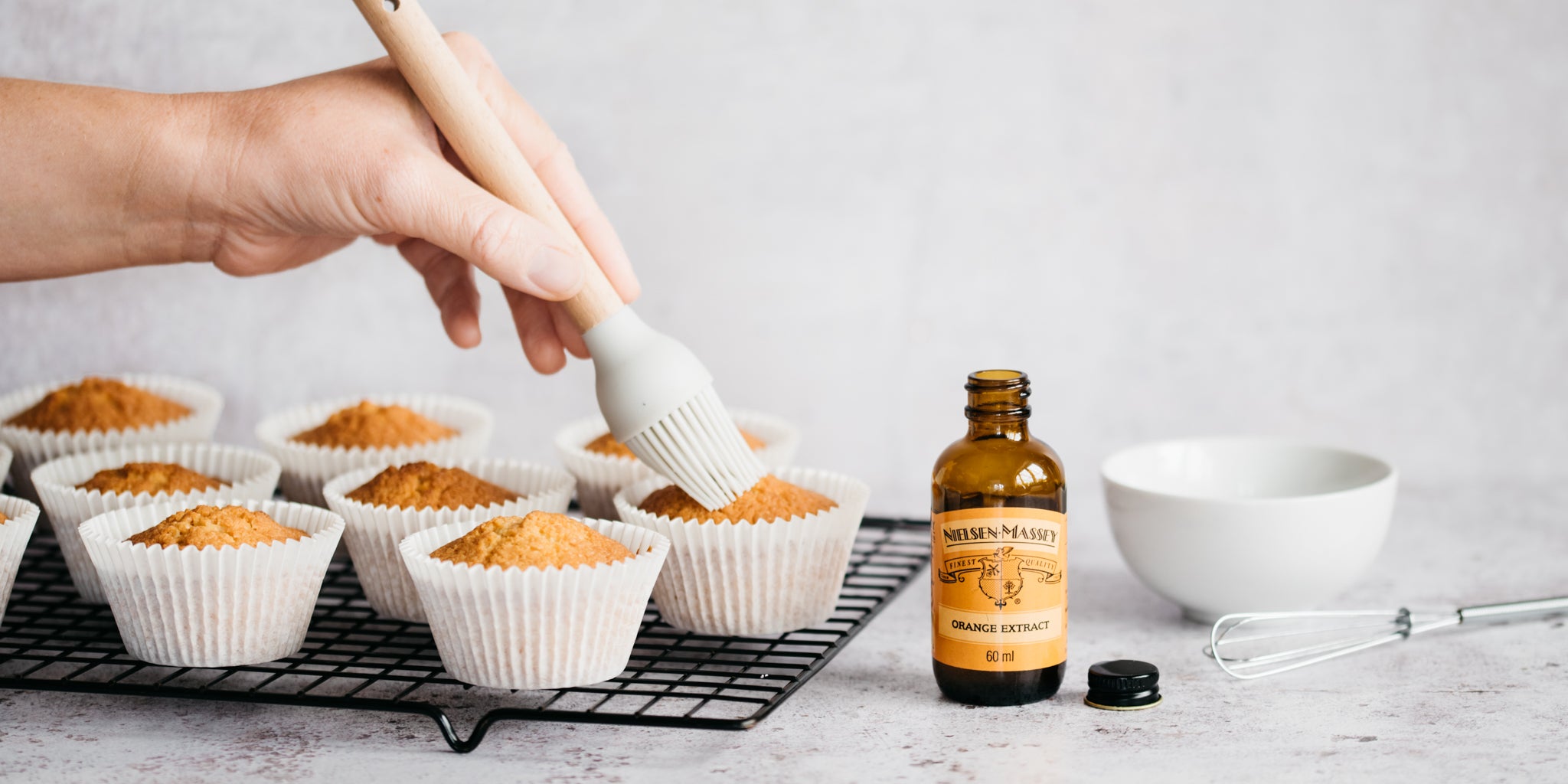 A fresh batch of Orange Blossom Cupcakes being brushed with orange blossom extract to infuse the cakes