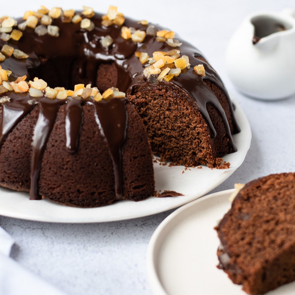 chocolate orange bundt cake on plate with chocolate drizzle on top with candid orange peel