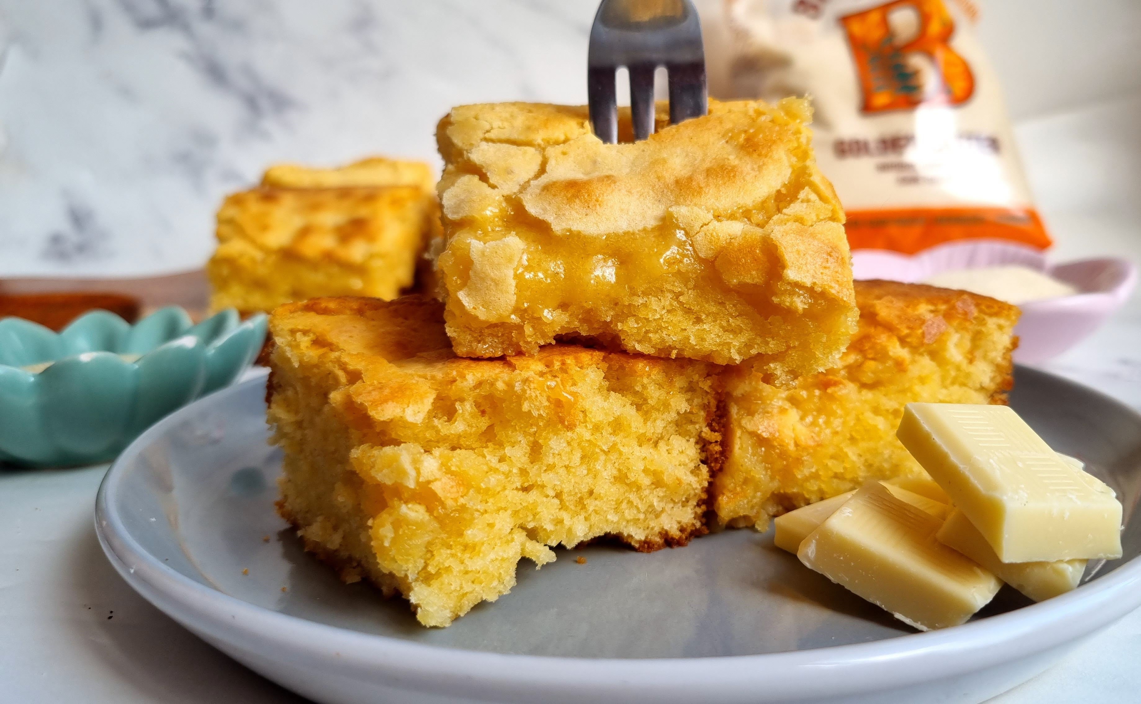 Plate of white chocolate brownies with a fork skewering the top brownie