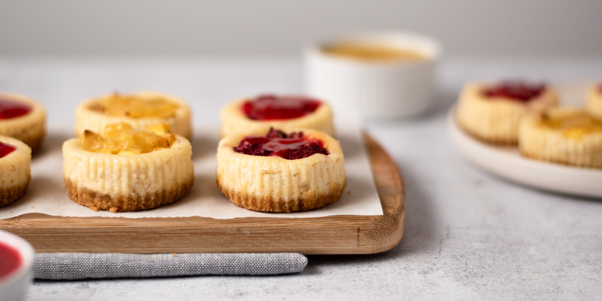 Mini cheesecakes topped with fruit on a wooden board