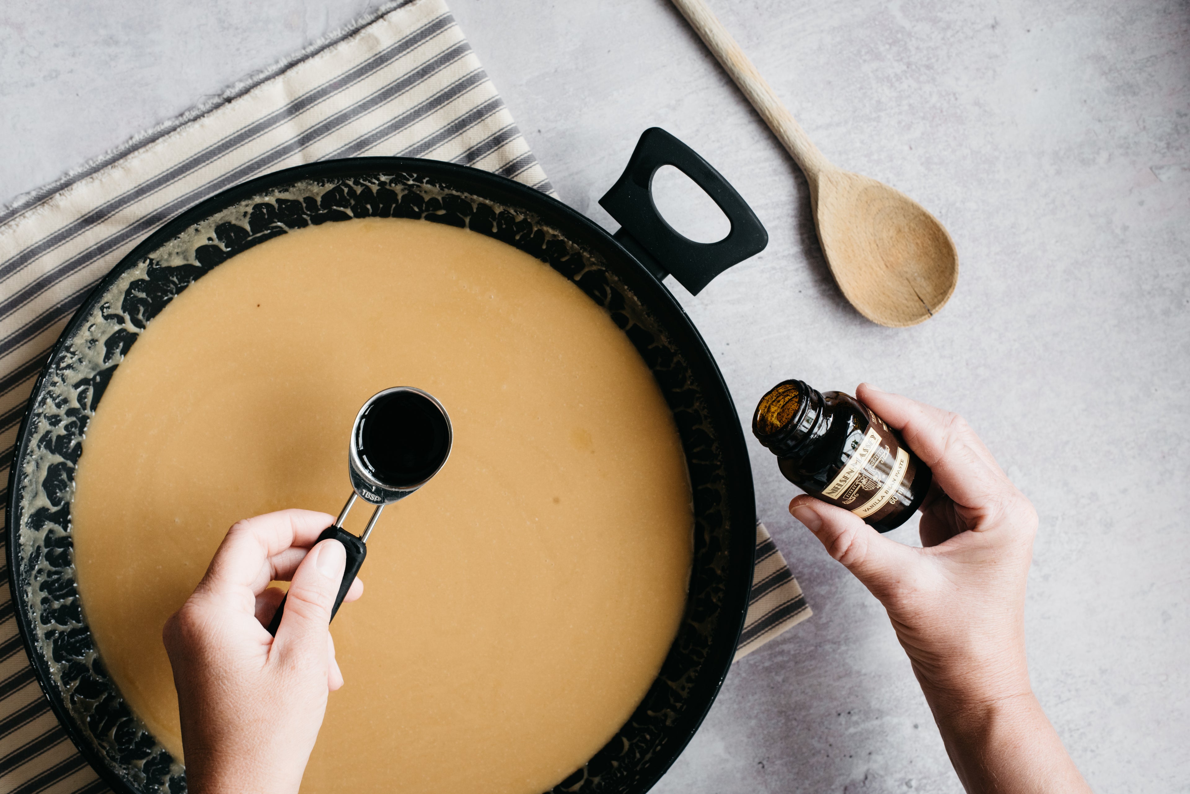 Vanilla bean paste being poured into a saucepan of fudge mixture