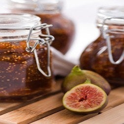 Fresh homemade fig jam in glass jars, next to chopped figs 