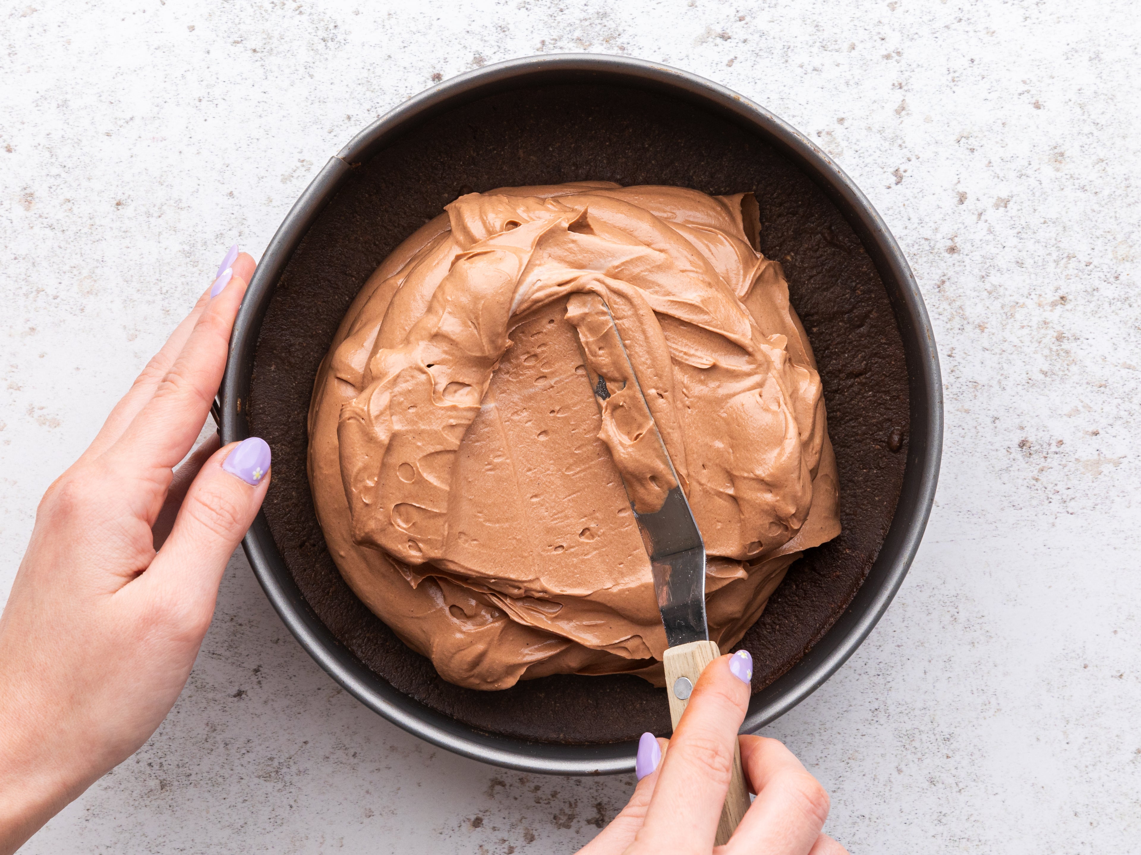 Chocolate Cheesecake filling being spread on top of a base in circular tin