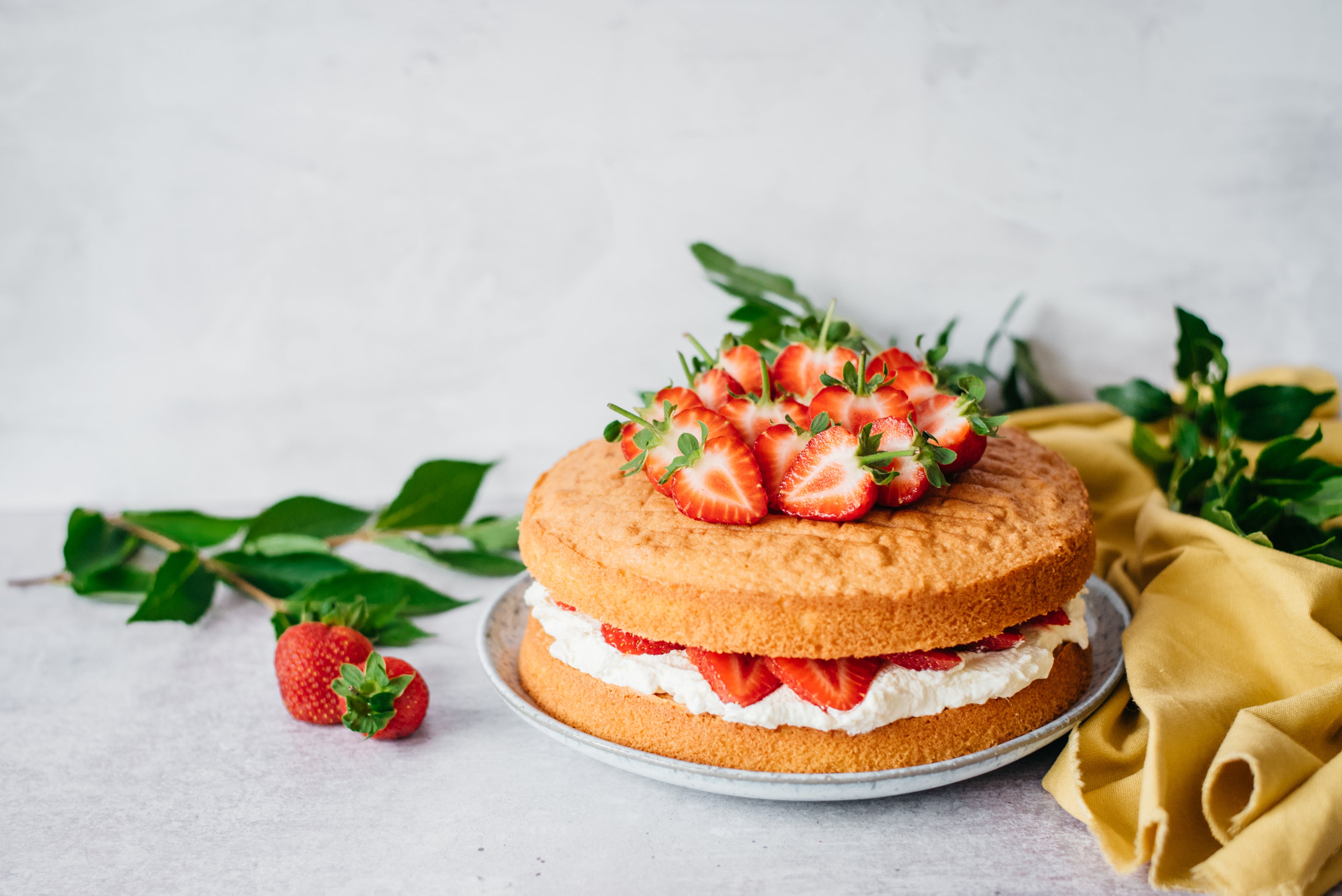 A low sugar victoria sponge cake topped with sliced strawberries
