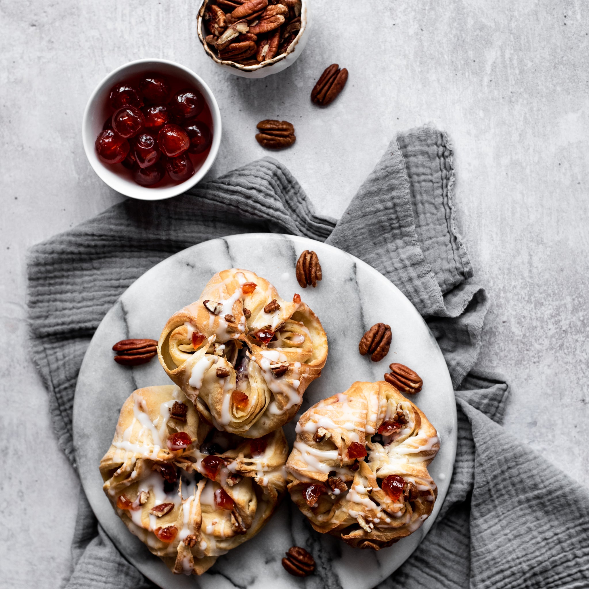 Over head plate of three danish pastries with pecan nuts and cherries