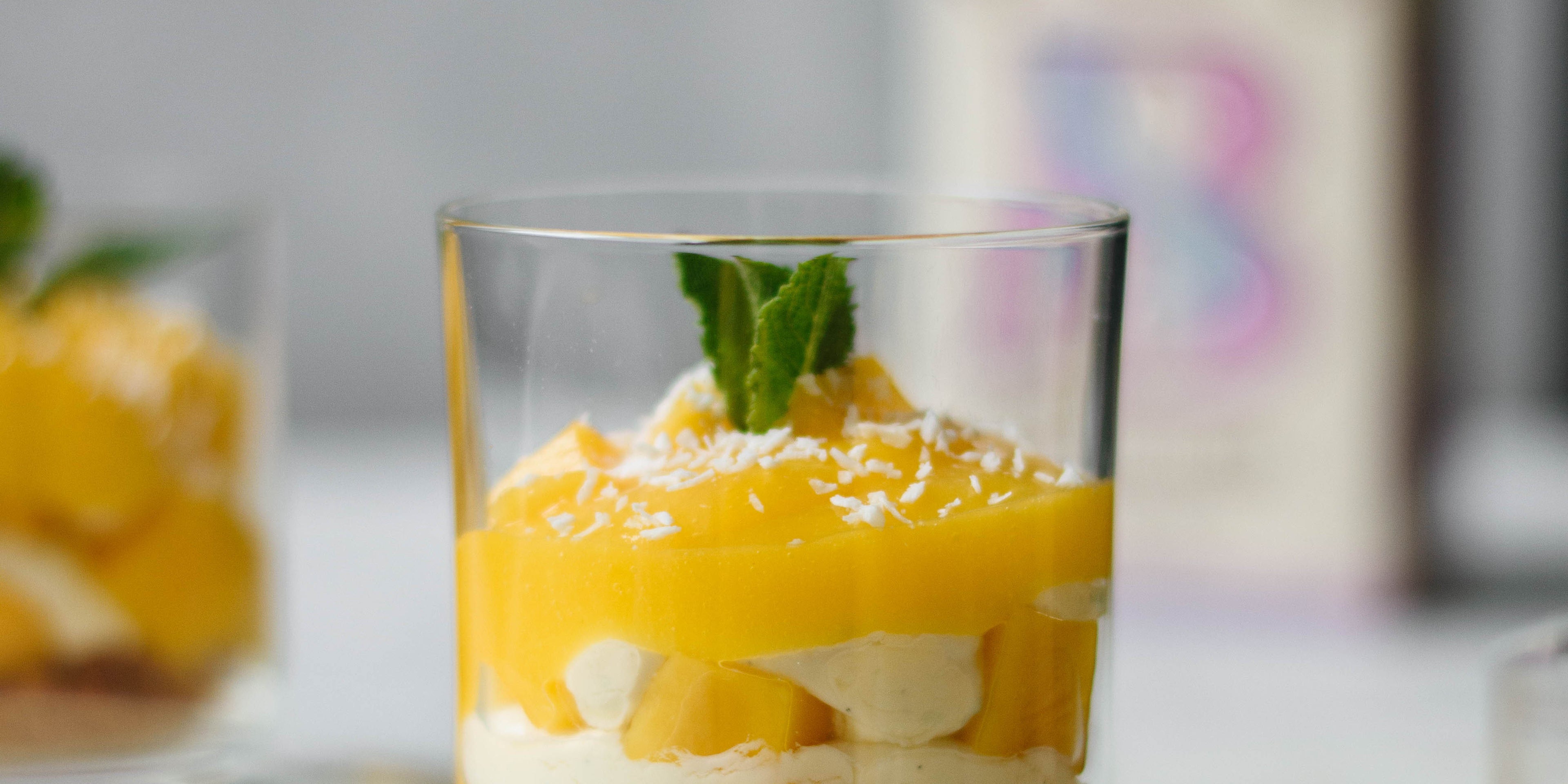 Close up of small glass of mango syllabub with sprig of mint on top