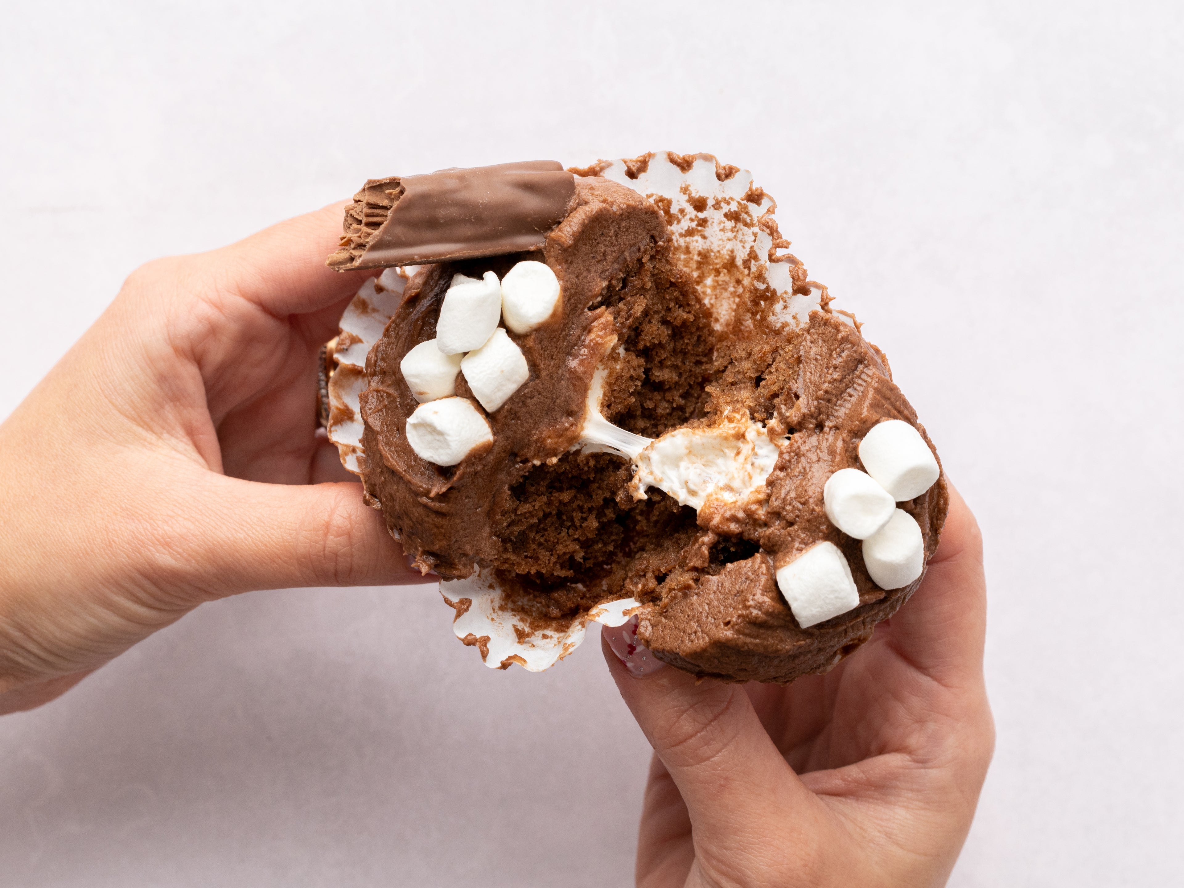 Hand tearing apart a chocolate cupcake