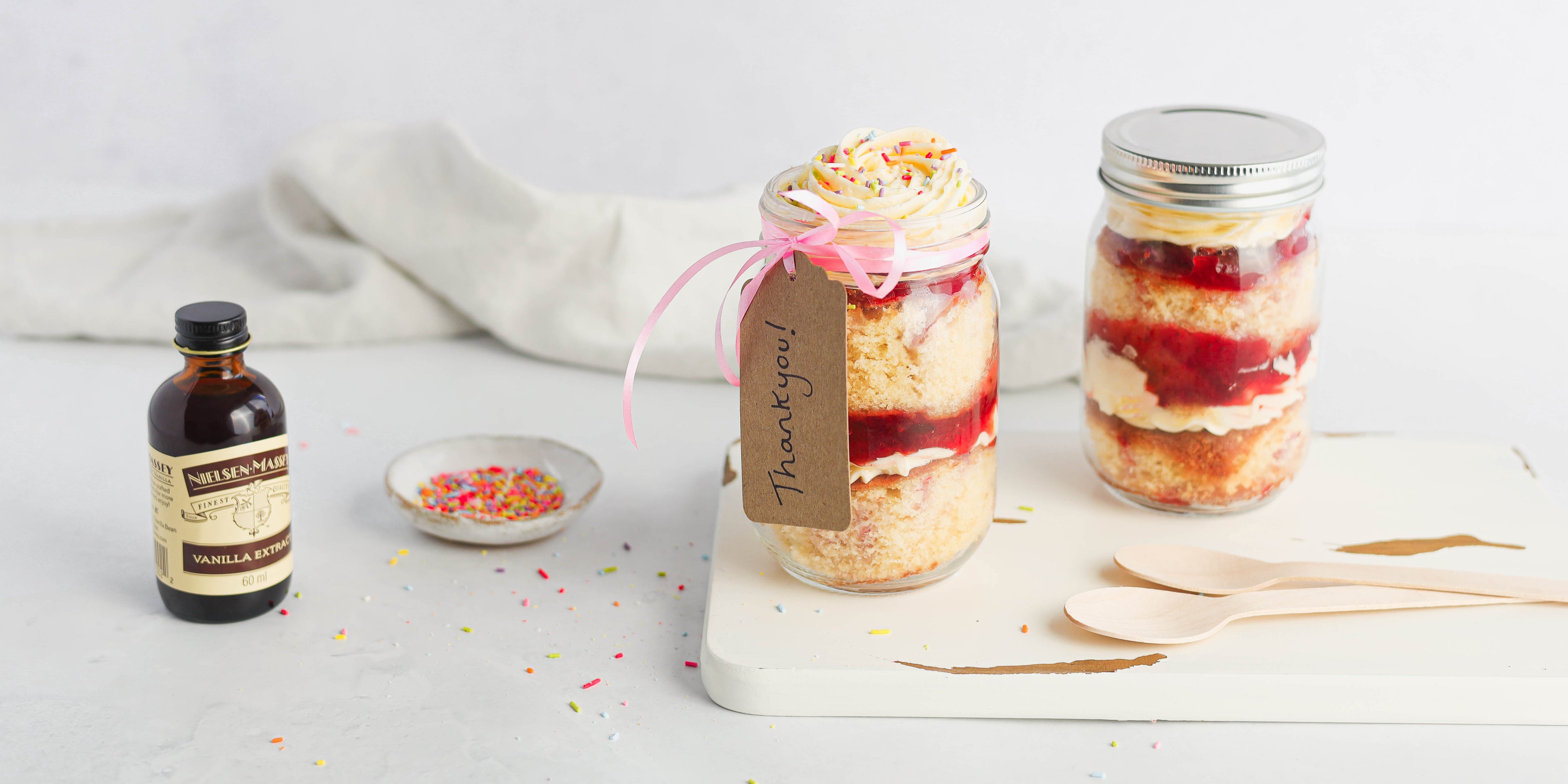 Vanilla Cupcake in a Jar, next to a bottle of Neilsen-Massey vanilla extract and a bowl of sprinkles