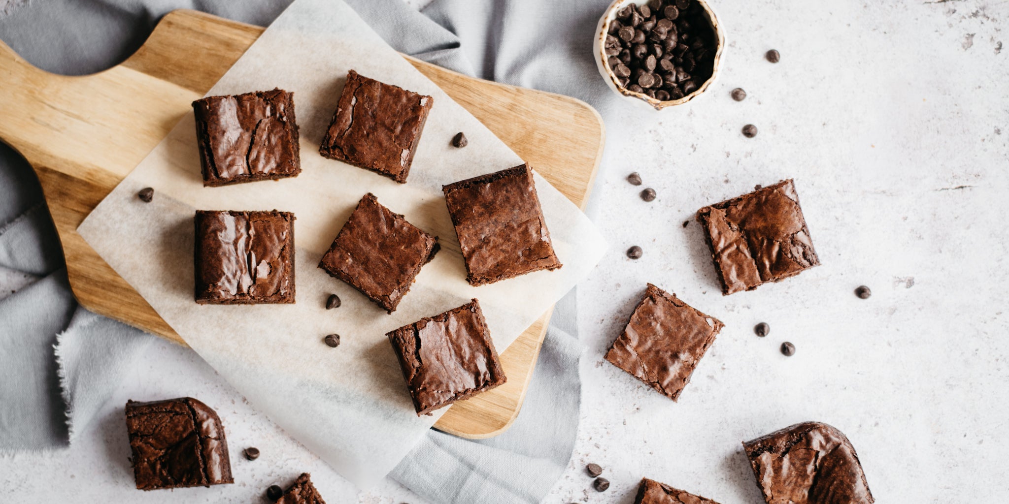 Top view of Wholemeal Chocolate Brownie squares served on parchment paper scattered with chocolate chips