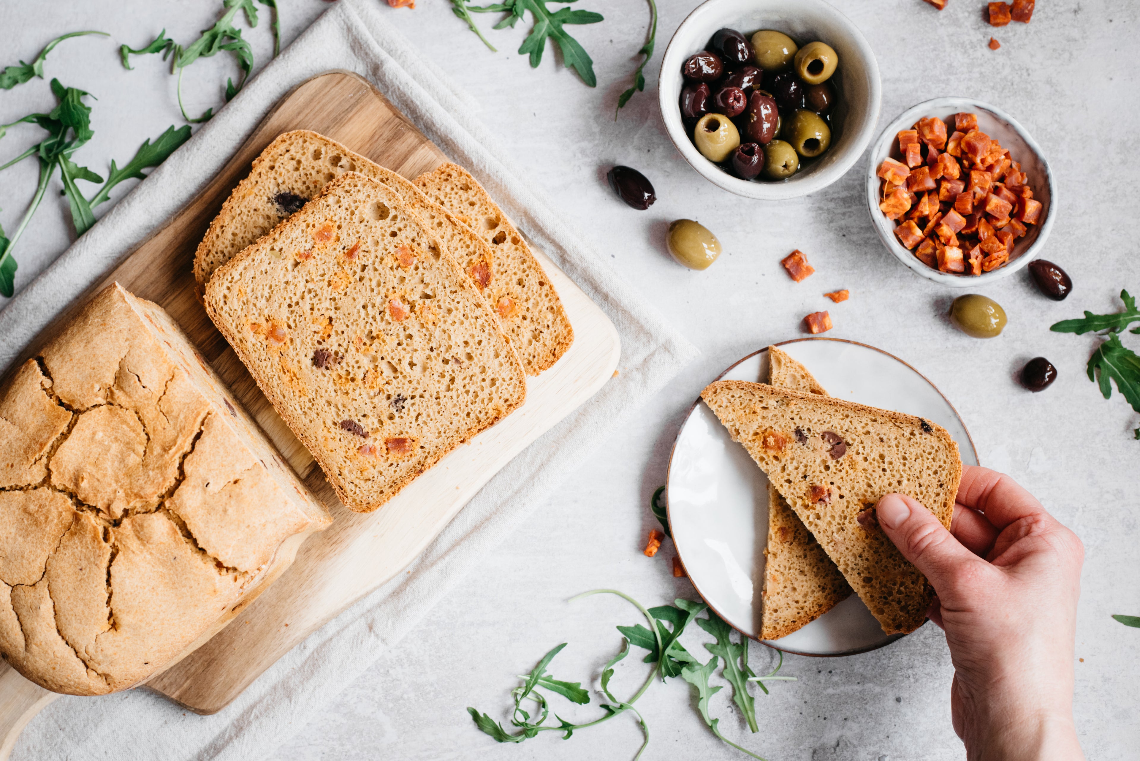 Over head shot of bread loaf and slices. Two slices on a plate and bowl of chorizo and olives