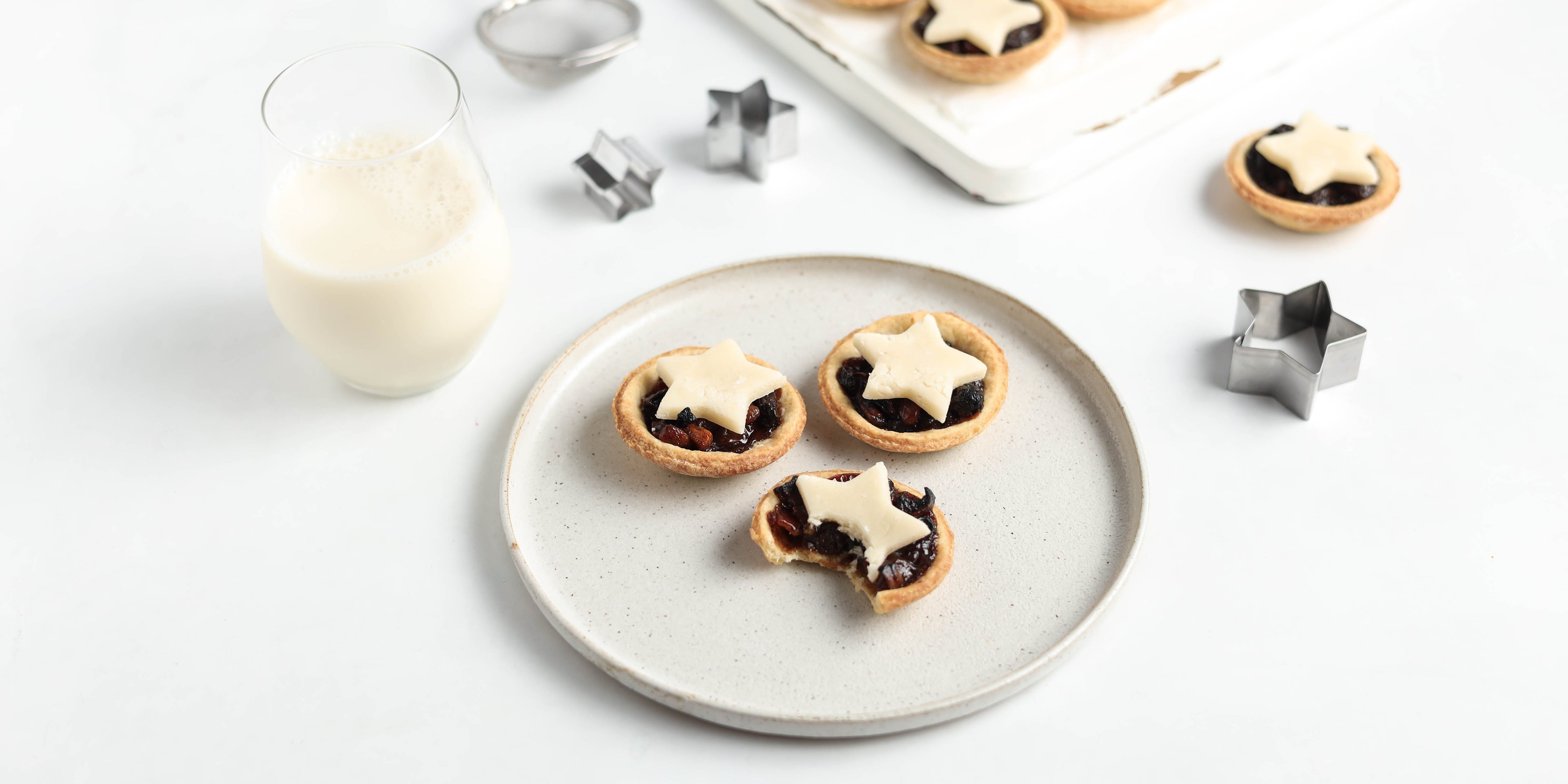 A plate of three mince pies with a glass of milk