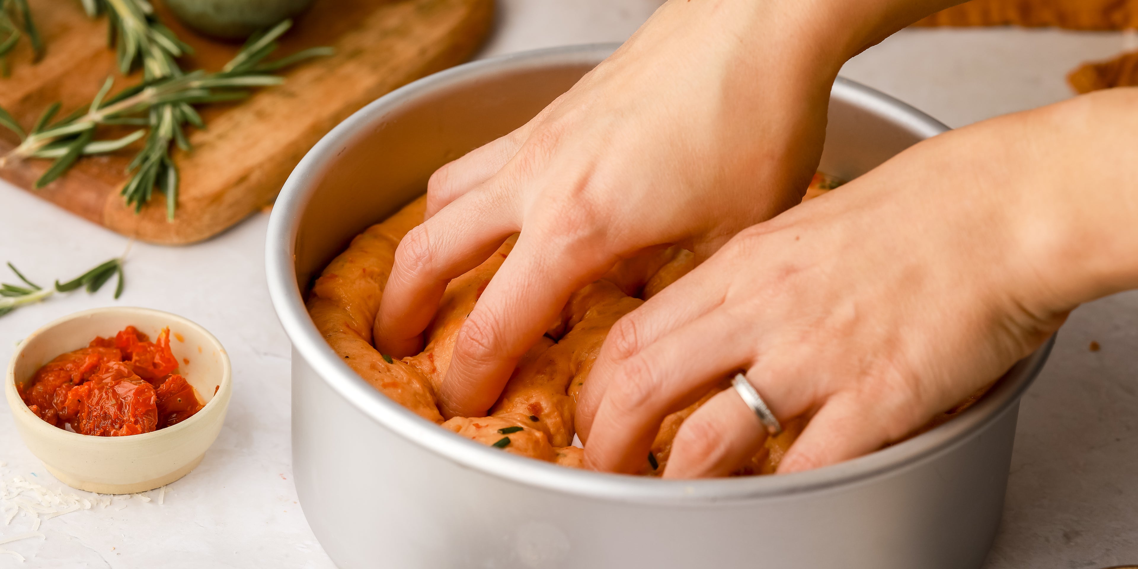 Gently pressing sundried tomato bread tough into a baking tin