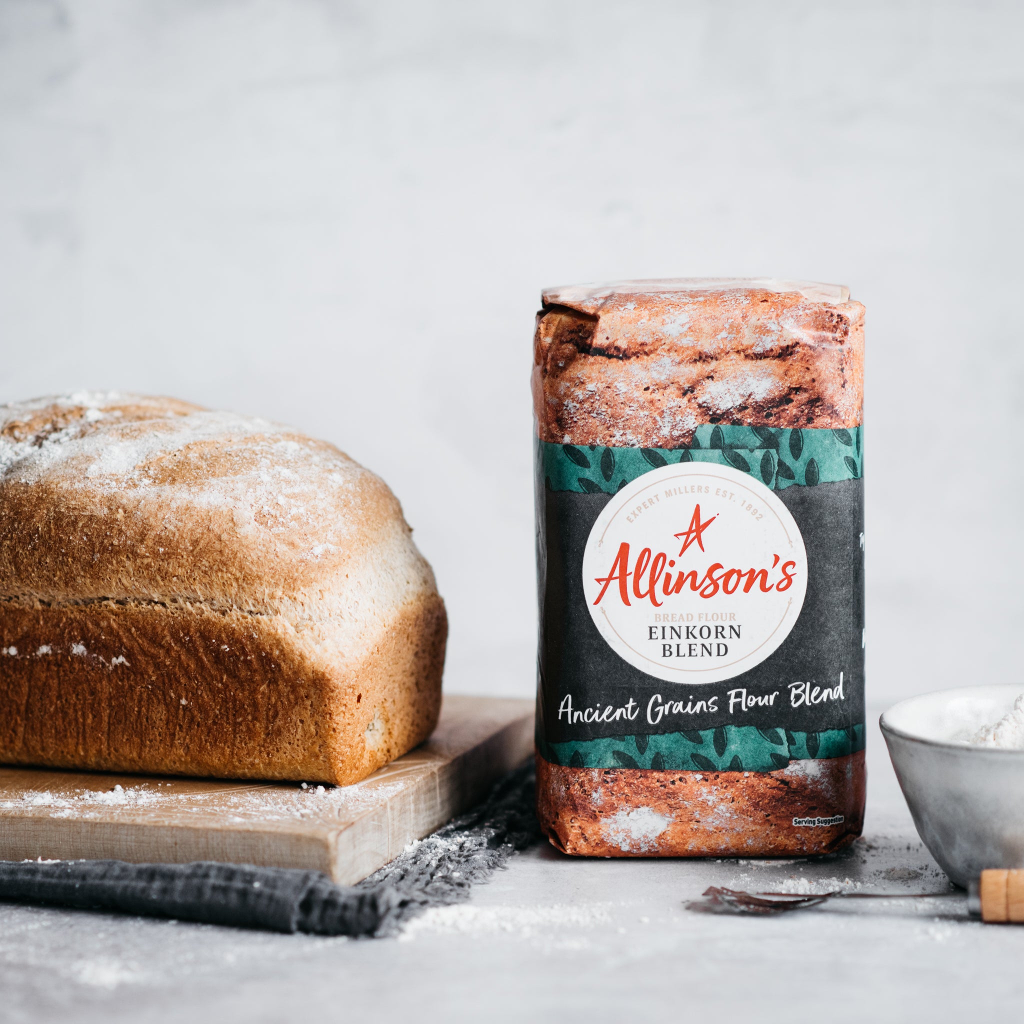 Einkorn bread loaf on chopping board with flour pack