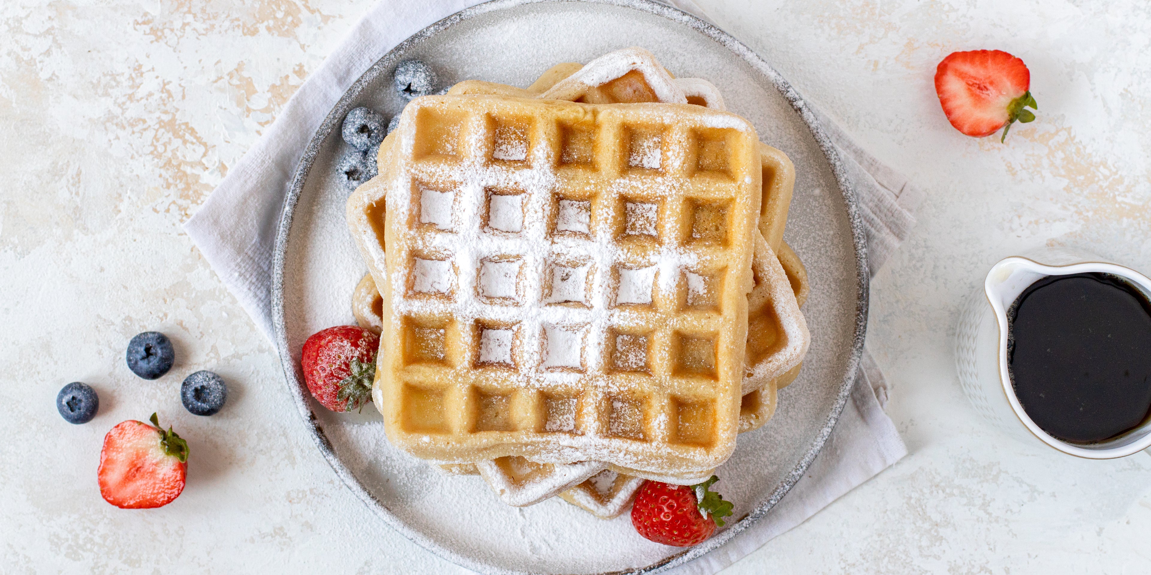 Top down view of gluten free vegan waffles topped in sugar and berries