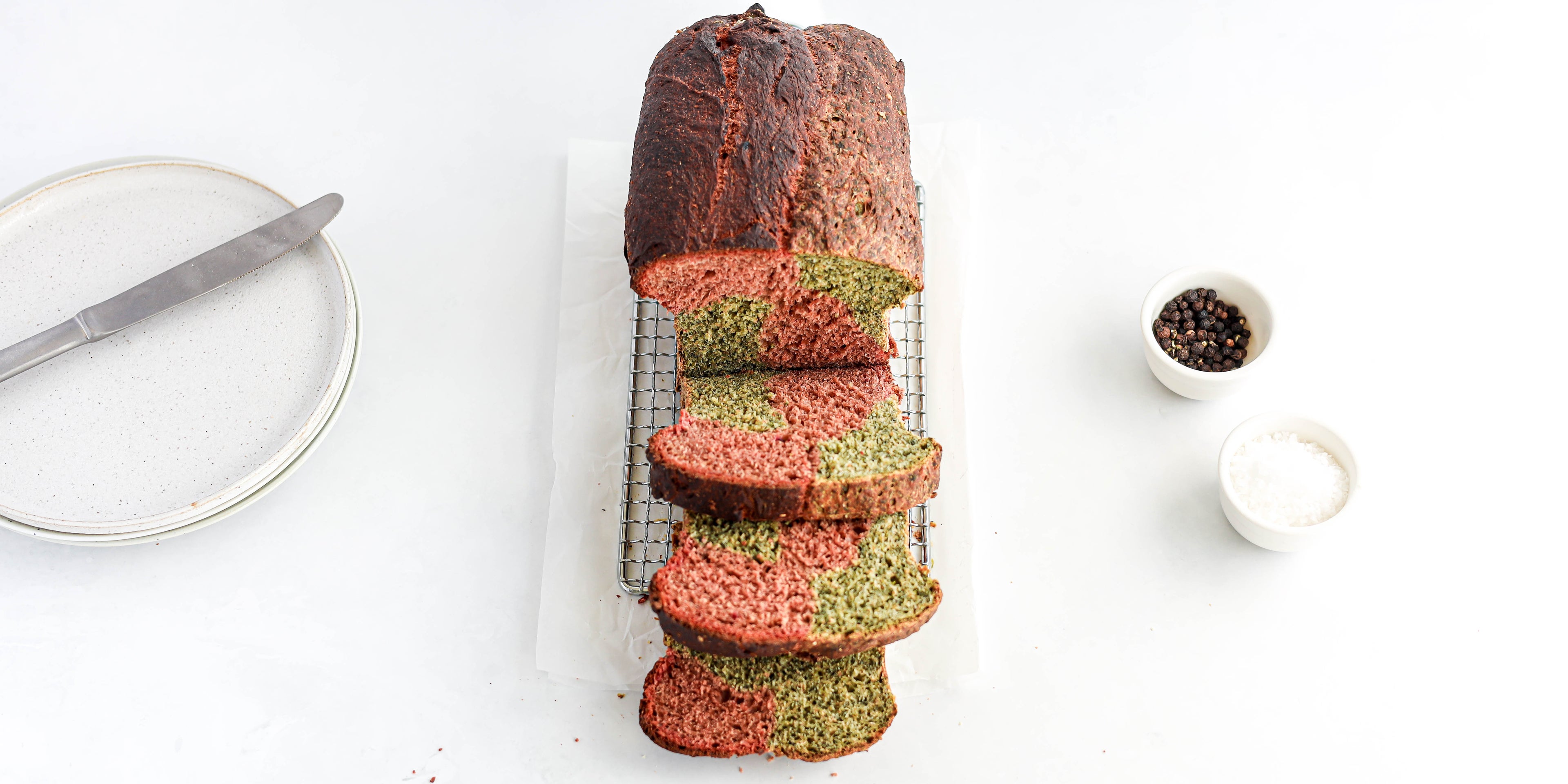 Top view of Marble Vegetable Bread being sliced on a wire rack, showing the pink and green insides