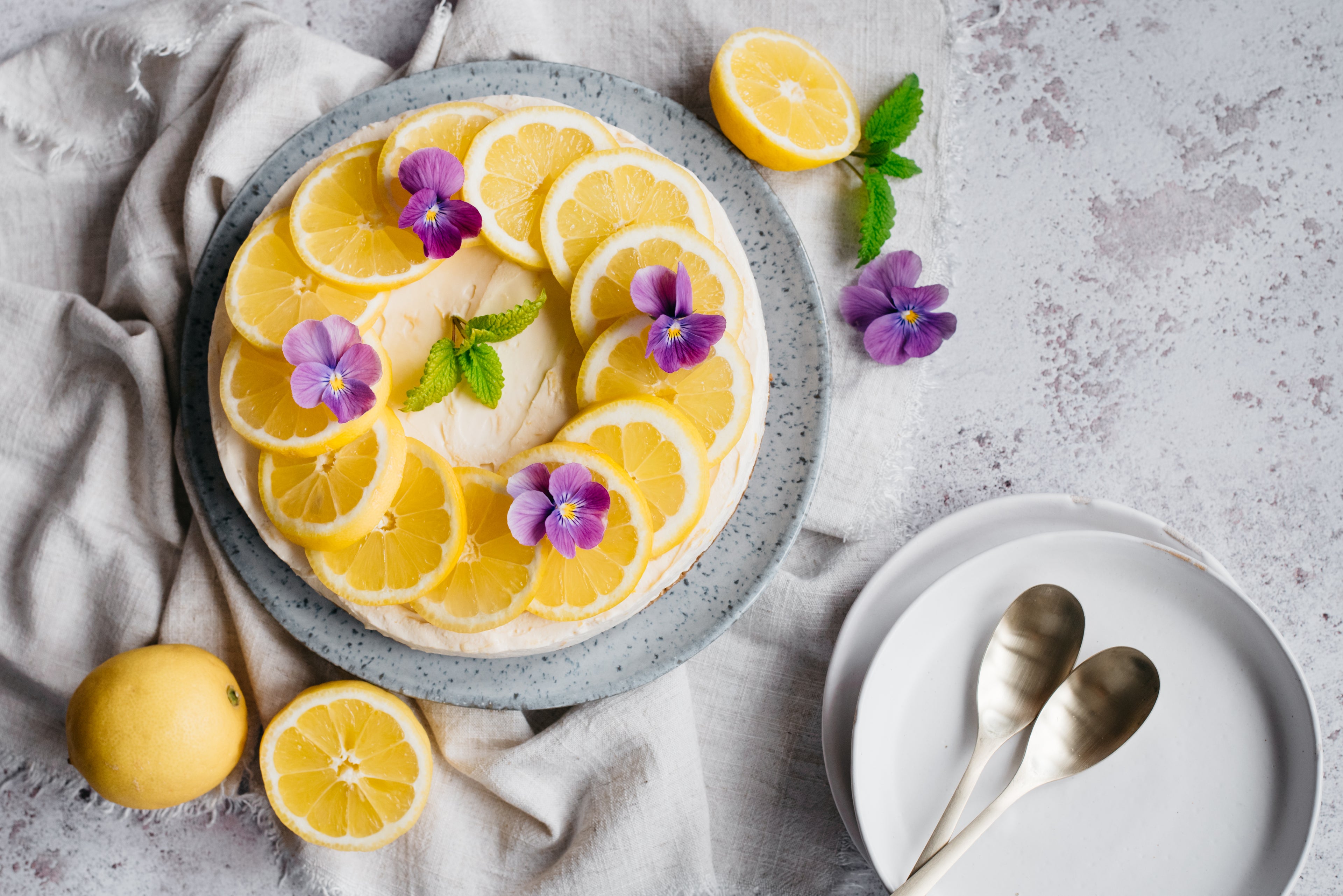 Overhead shot of lemon cheesecake with lemon and purple flower decoration