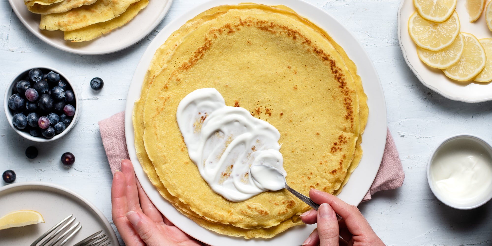 Top down view of yoghurt being smothered onto a turmeric and lemon pancake